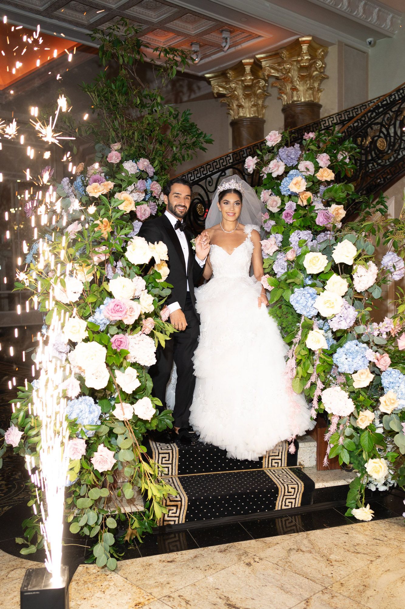 Elegant wedding reception decor featuring white and blue hydrangea floral arrangements with twinkle lights and greenery.