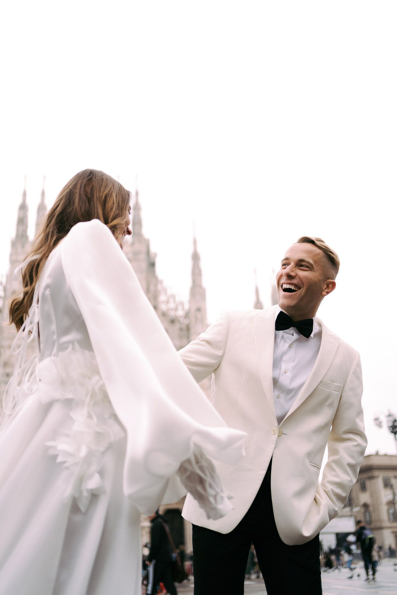 A series of joyful moments captured in white outfits against a blurred architectural backdrop.