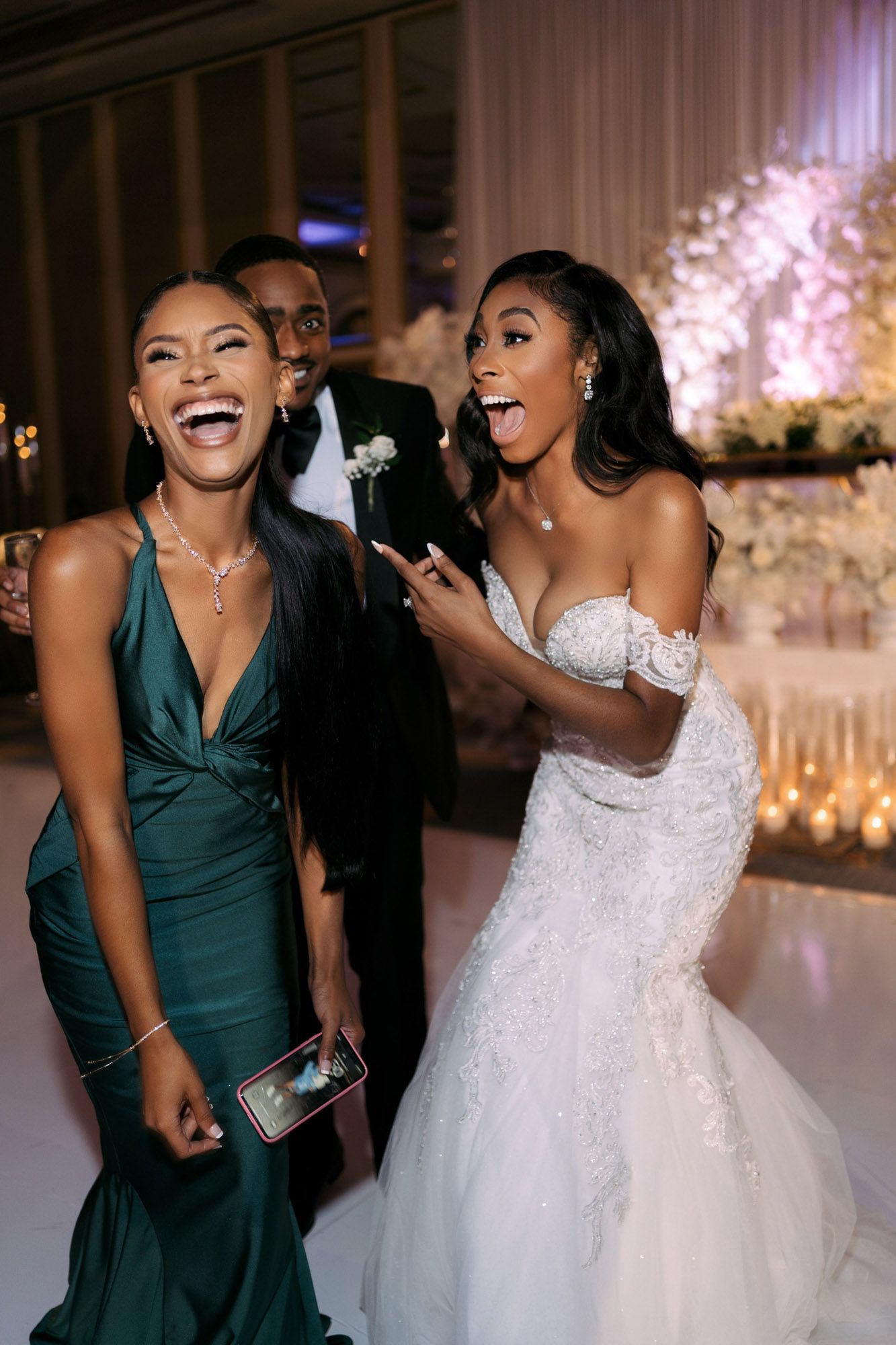 Wedding party members in emerald green dresses dance and celebrate with the bride in a beautifully decorated reception venue.