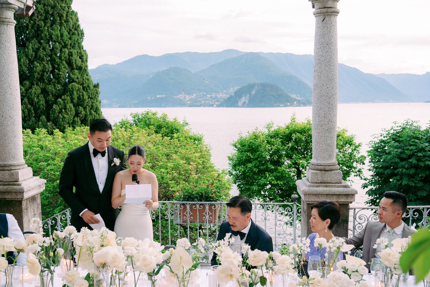 Elegant outdoor wedding reception table overlooking a scenic lake and mountains in Italy.
