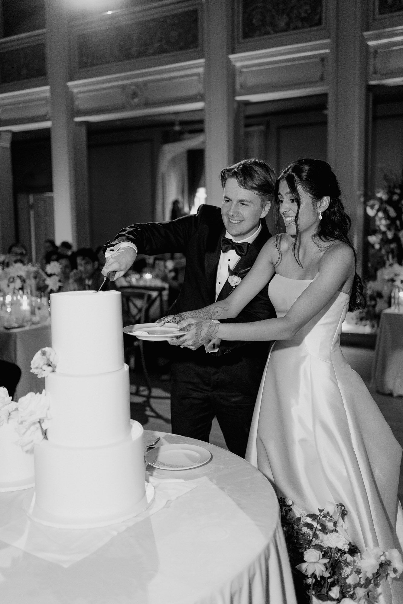 A wedding cake cutting sequence shown in multiple progressive black and white photos at an elegant reception venue.