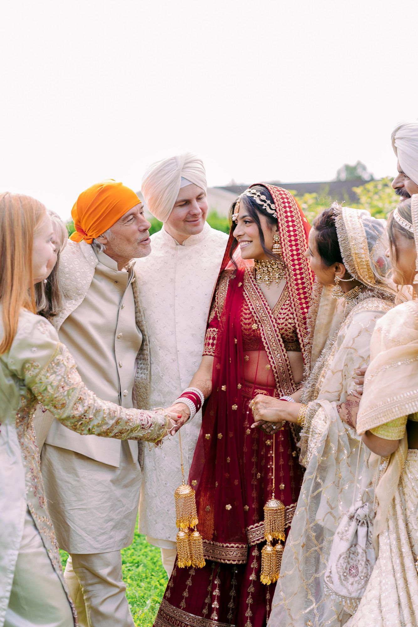 A traditional Sikh wedding ceremony shows couples in colorful traditional attire including red and gold lehengas and turbans.