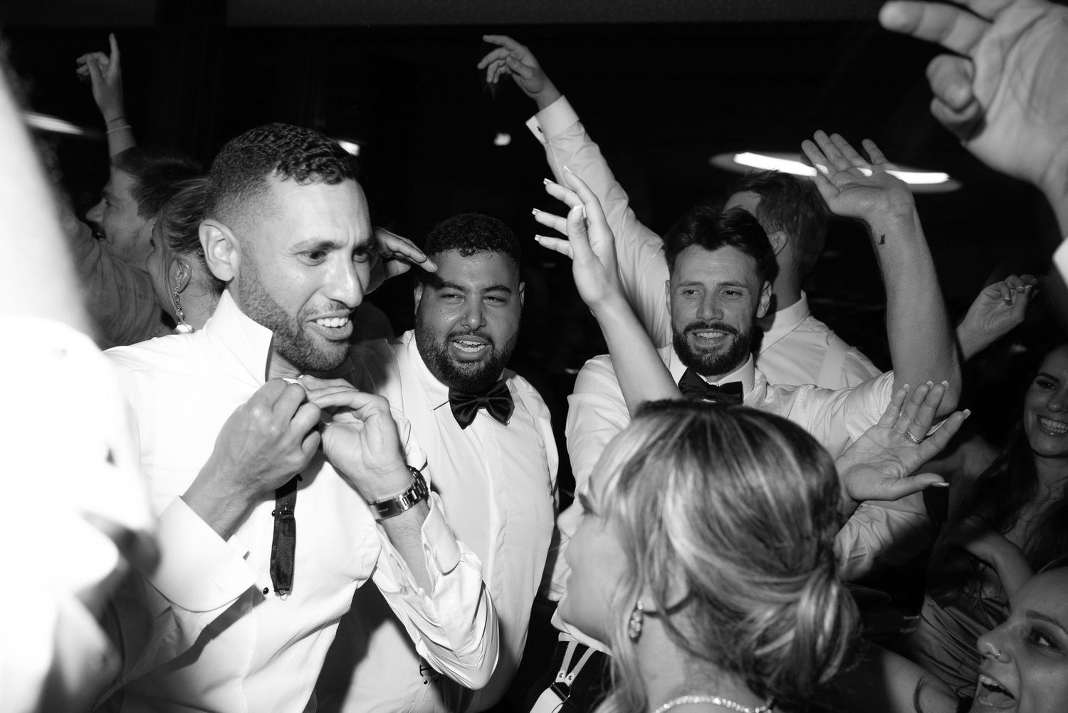 A group of people dancing and celebrating at a lively party with hands raised in the air.