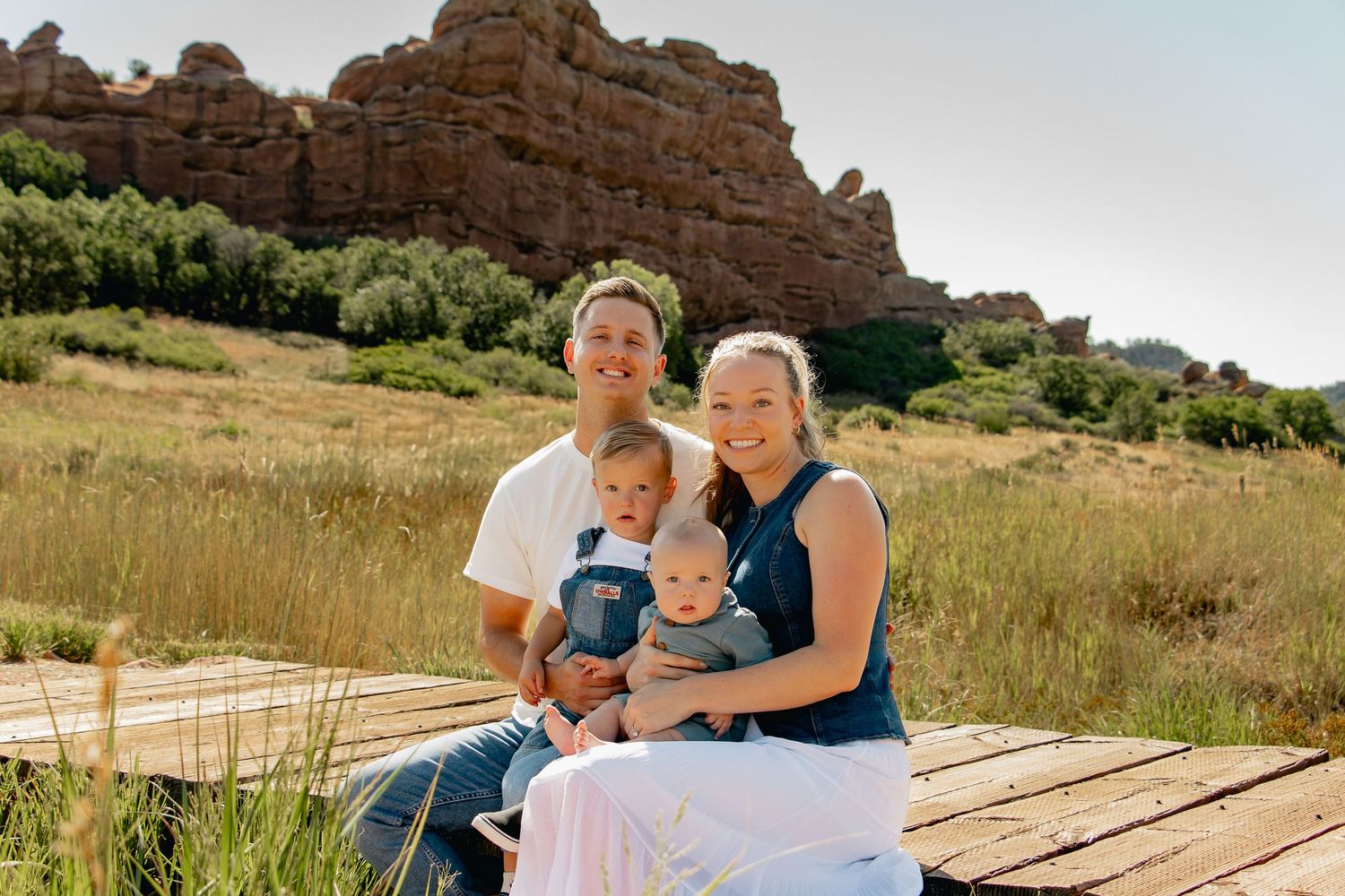 People enjoy a sunny day sitting together on rustic wooden steps in an outdoor natural setting.