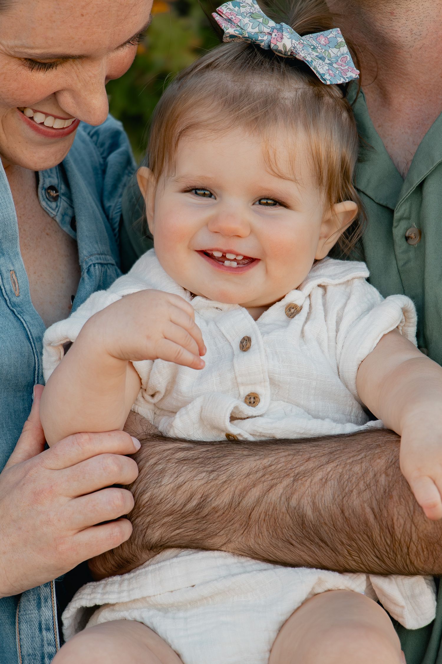 A baby in a white outfit smiles while being held, shown in a series of connected photos.