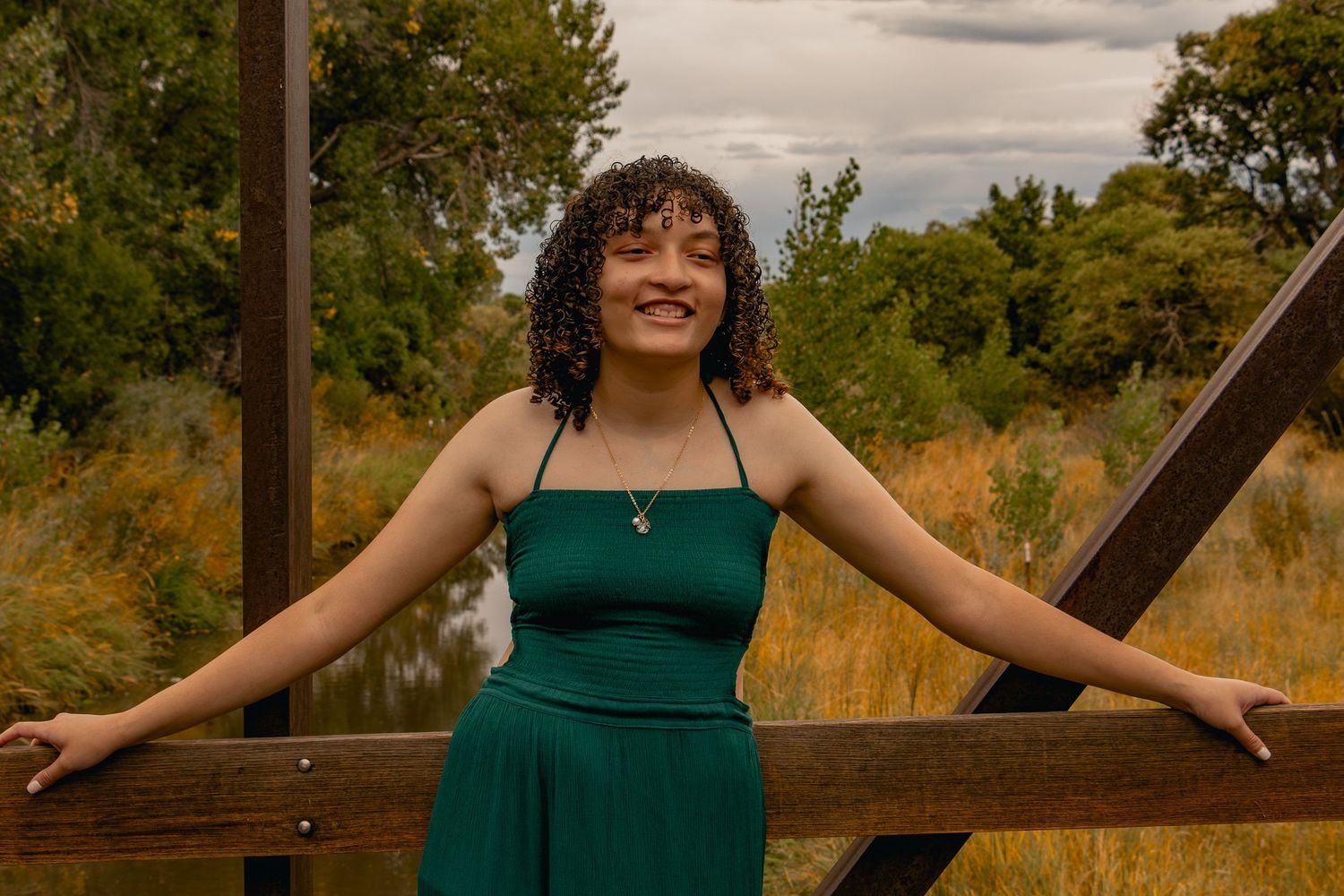 A photoshoot along a wooden pathway through autumn grass and trees during golden hour at sunset.