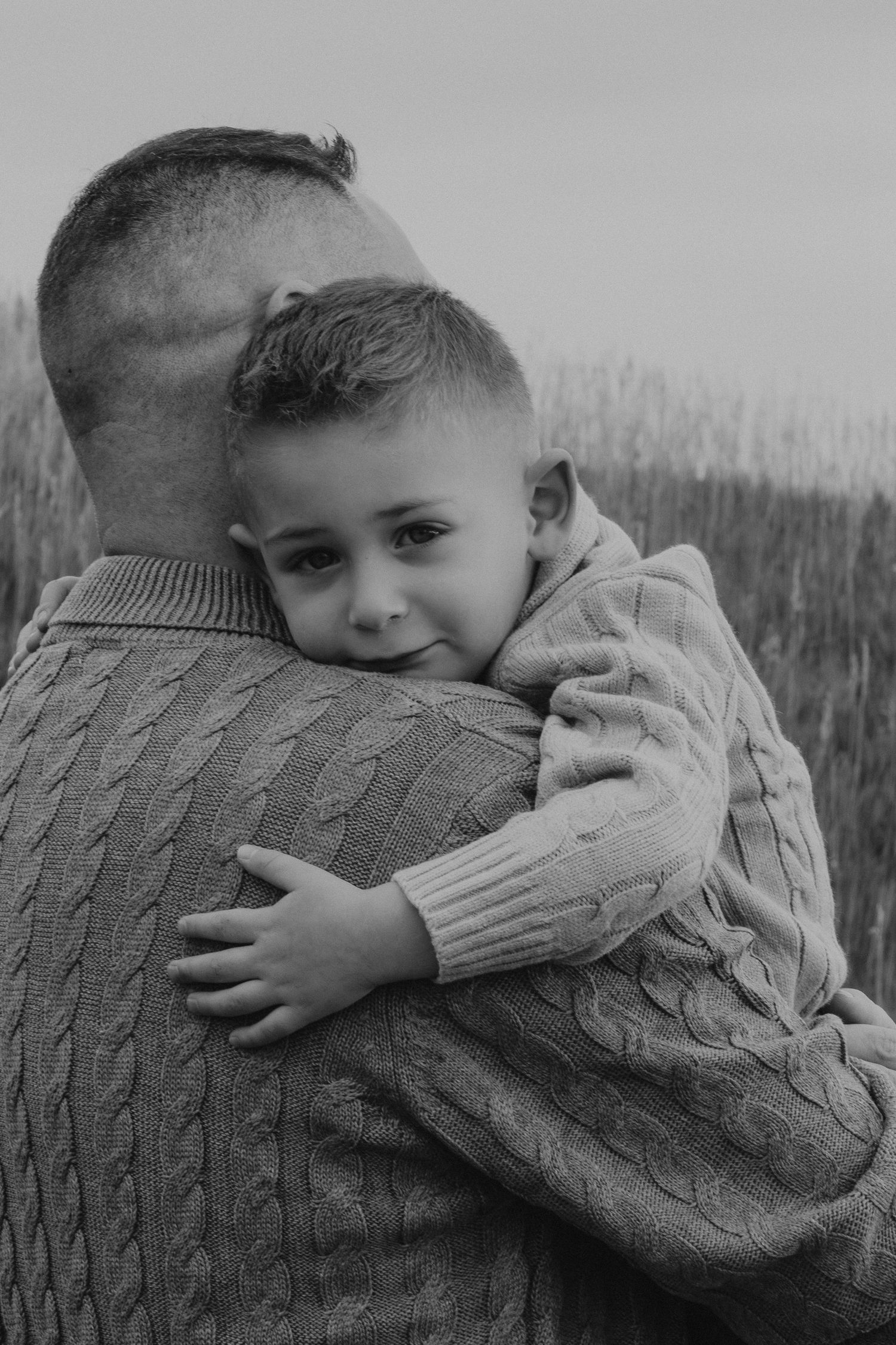 A series of black and white photos showing a child hugging and snuggling into a cozy cable knit sweater.