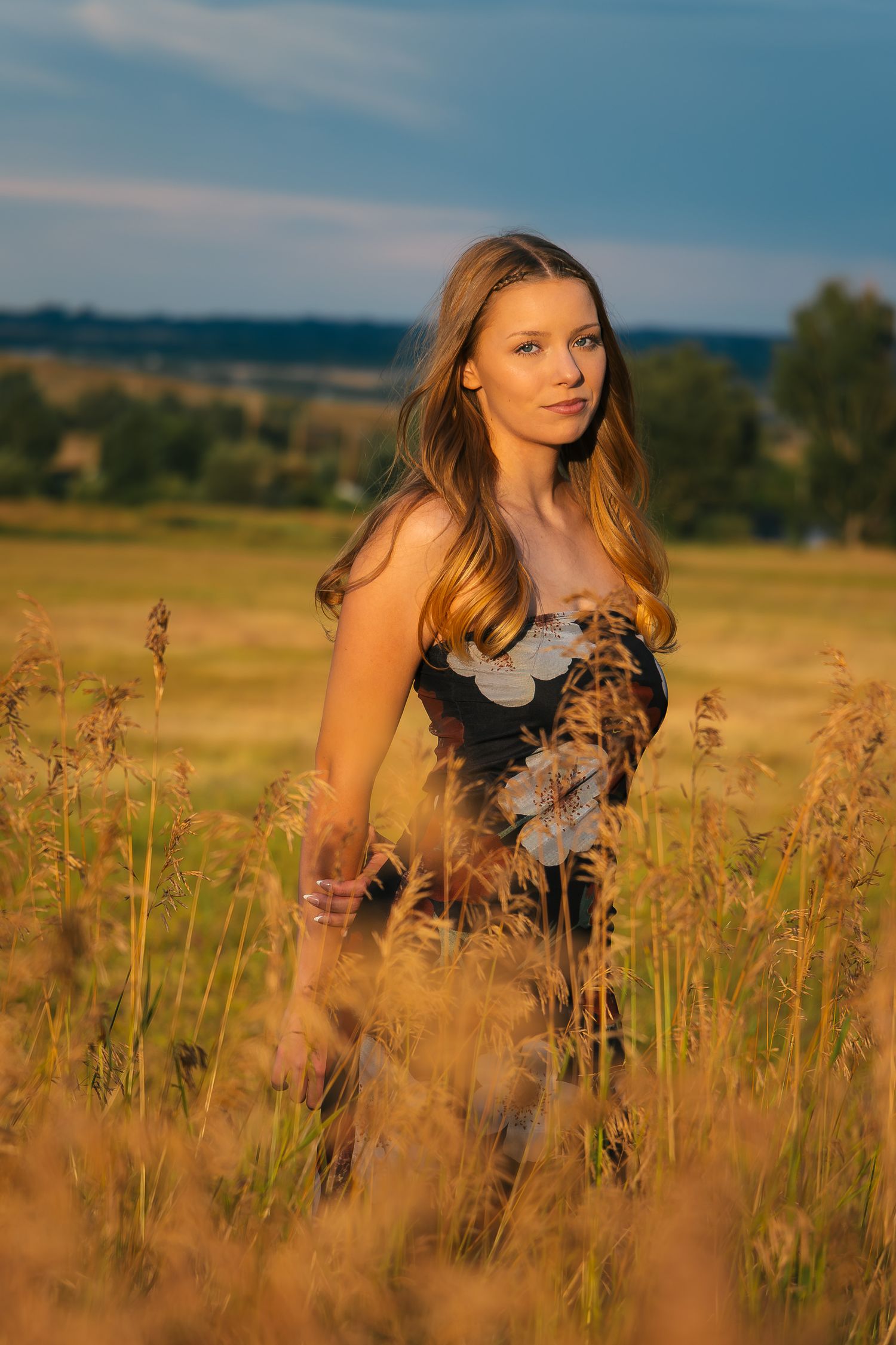 Golden hour portrait session in tall grass meadow with warm sunlight creating a dreamy natural atmosphere.