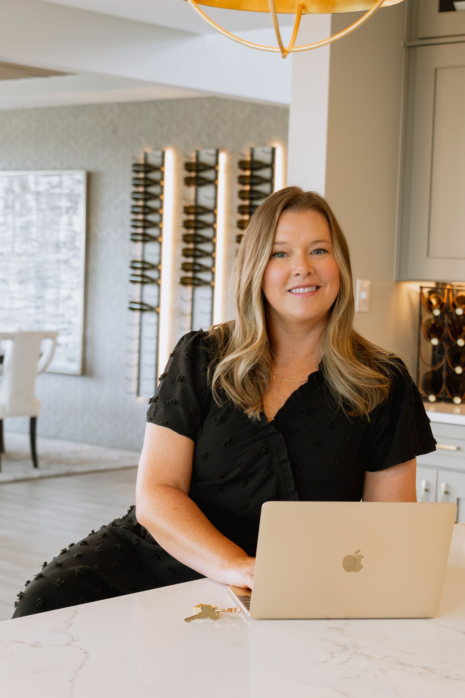 Professional workspace featuring a marble countertop with MacBook laptop and modern pendant light fixture overhead.