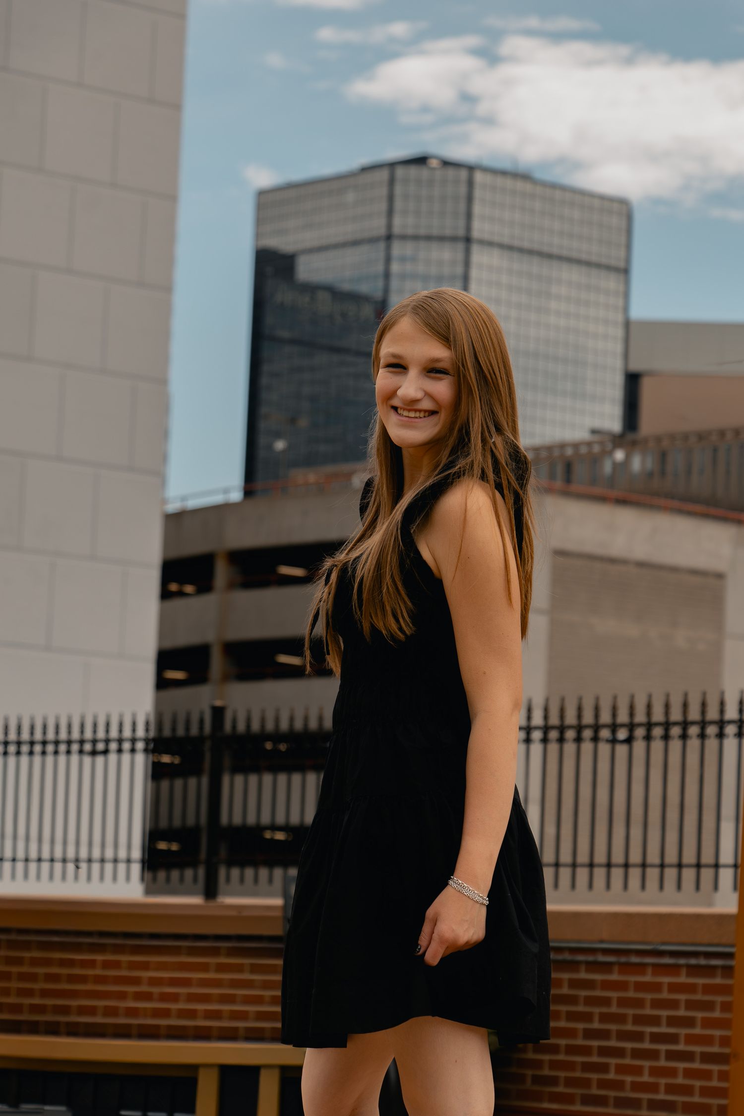 A series of outdoor portrait photos against urban architecture featuring brick walls and glass buildings on a sunny day.