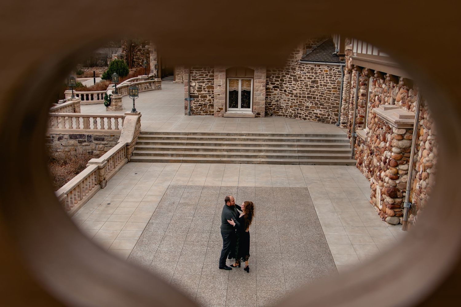 A couple embraces during a romantic photoshoot on stone steps at a historic European building location.