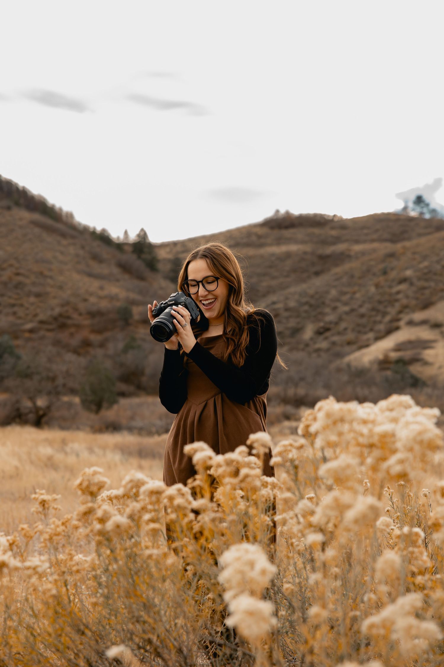 A photographer takes pictures among golden wildflowers in a mountainous desert landscape during autumn.