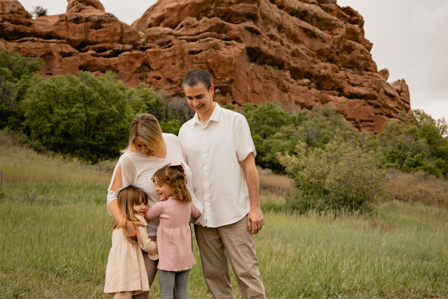 A group enjoying a sunny day against striking red rock formations at Red Rocks Park in Colorado.