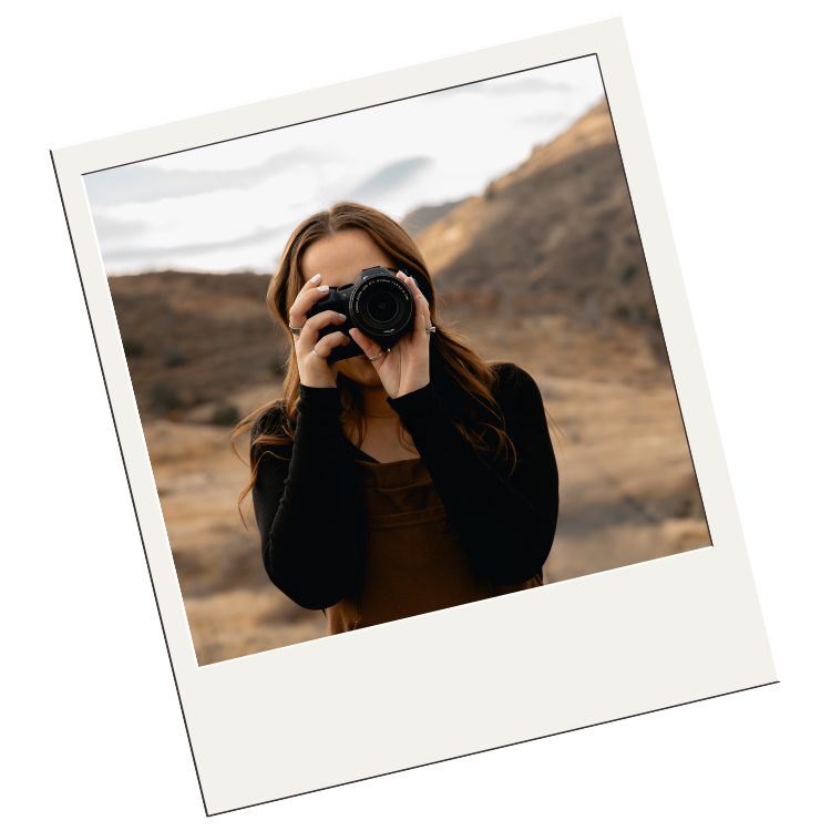 Photographer in silhouette against desert landscape taking photos with professional camera during sunset.