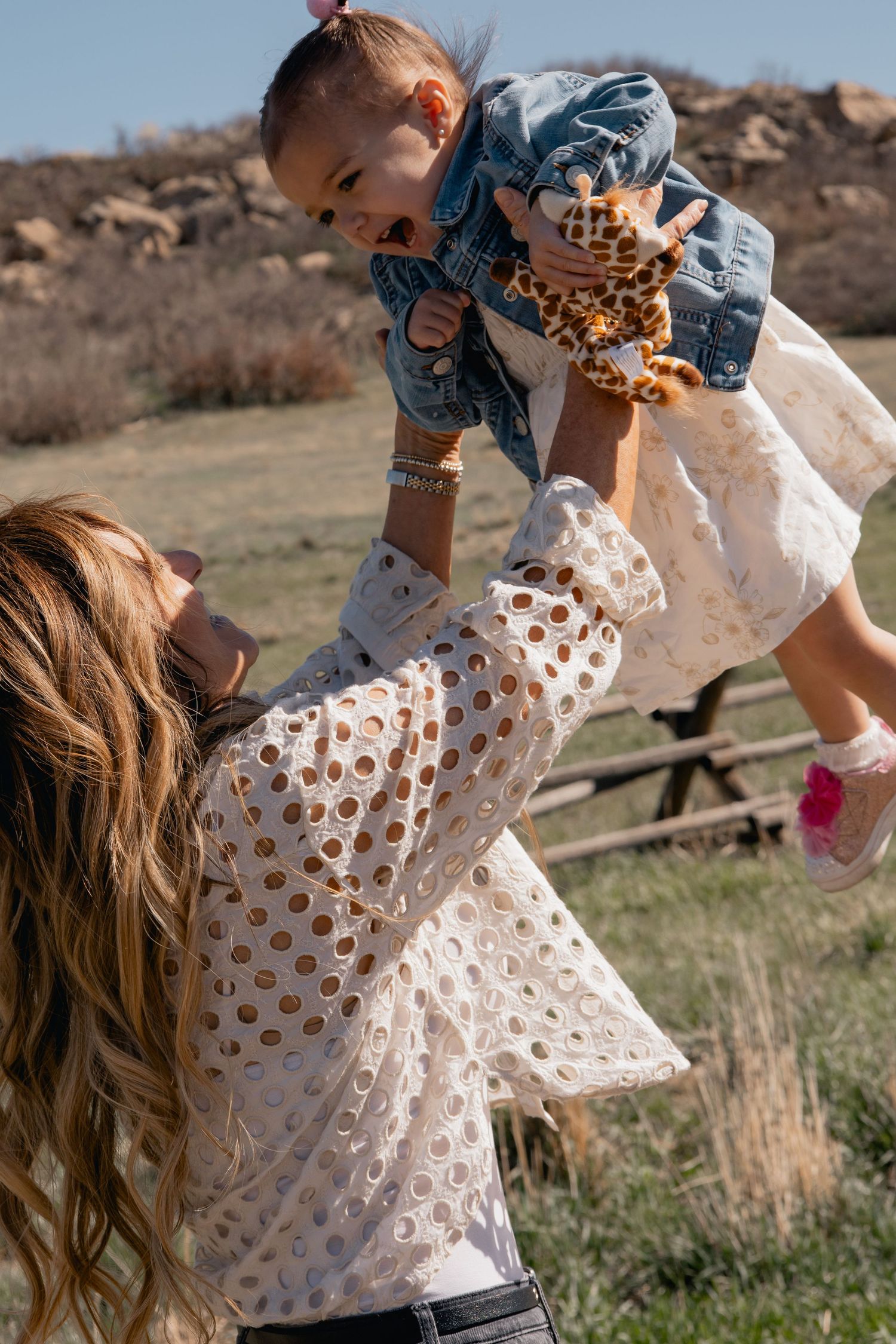 A joyful outdoor moment in nature with denim and polka dot clothing against a scenic rural background.