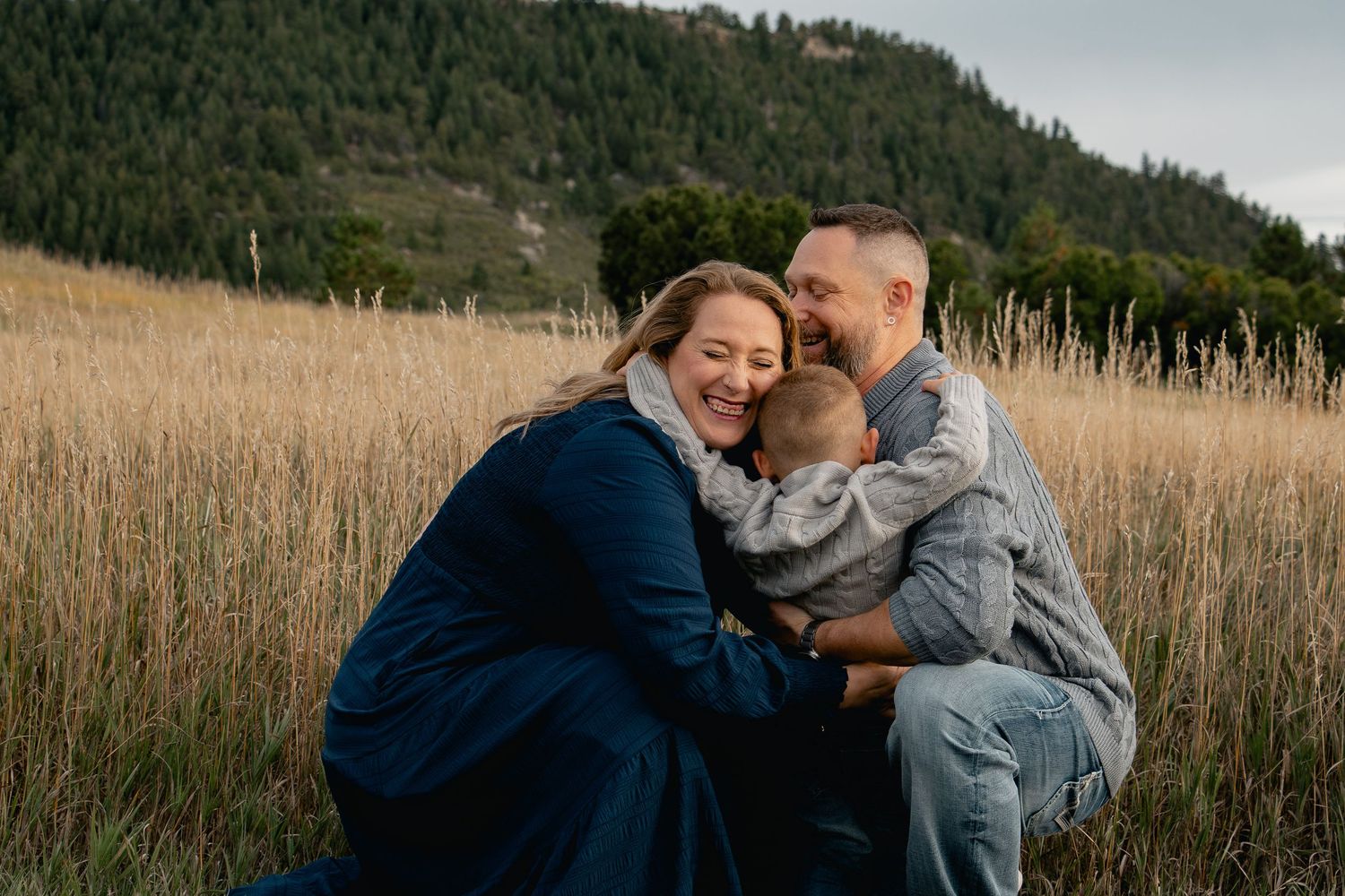 A couple embraces lovingly in a golden wheat field during sunset.