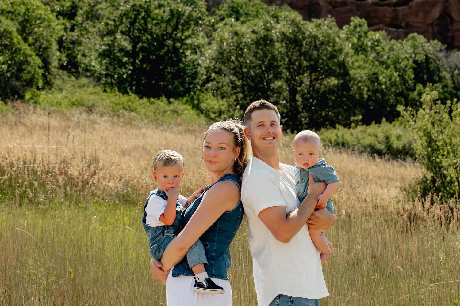 A family walks together through a scenic golden meadow on a sunny summer day enjoying nature.