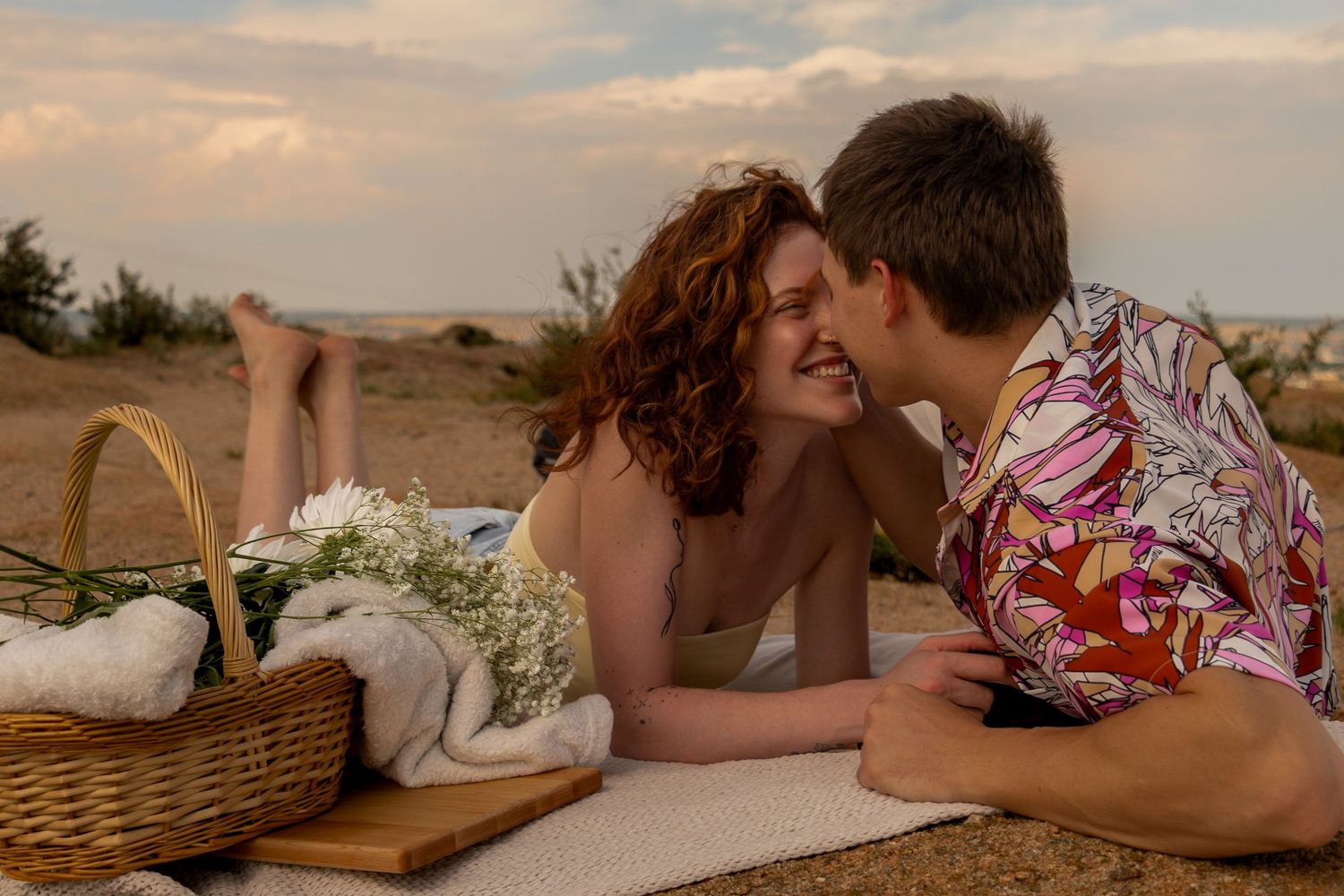Romantic couple enjoying an intimate moment during a dreamy sunset picnic on the beach.