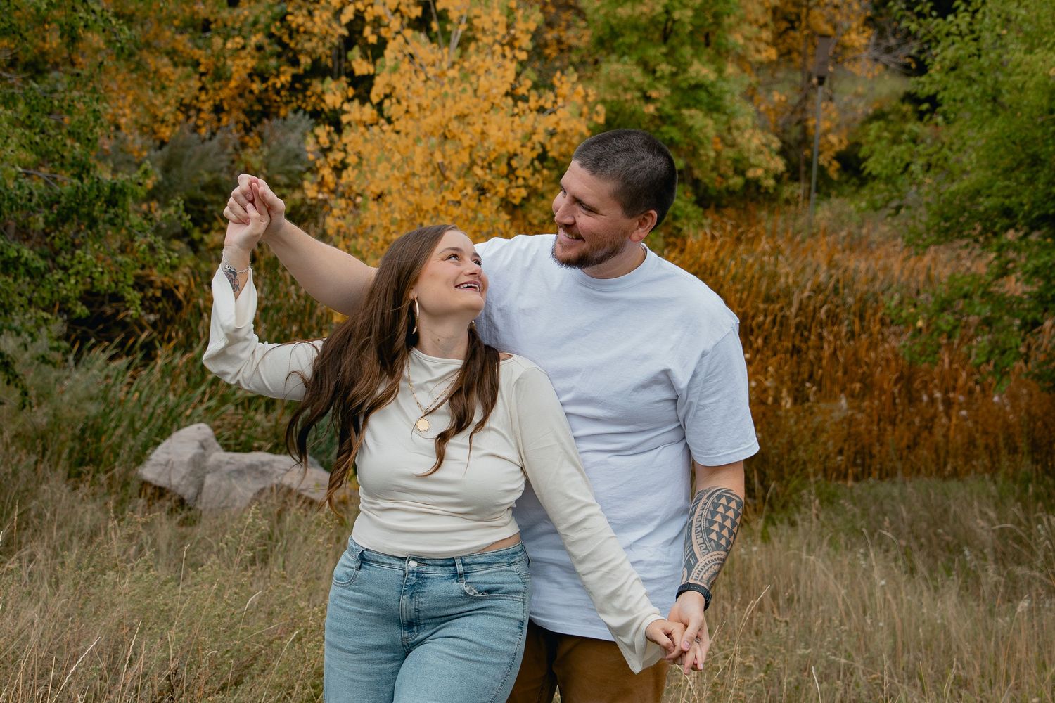 A couple shares tender moments together in a golden autumn field during a romantic outdoor photoshoot.