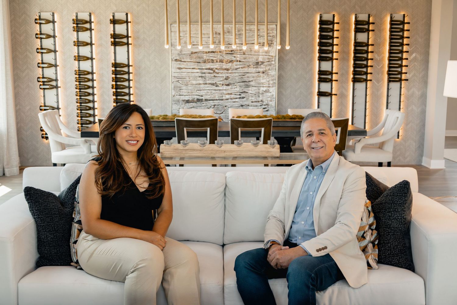Interior of a modern living room with a white sofa, decorative ladder wine racks, and a contemporary chandelier.