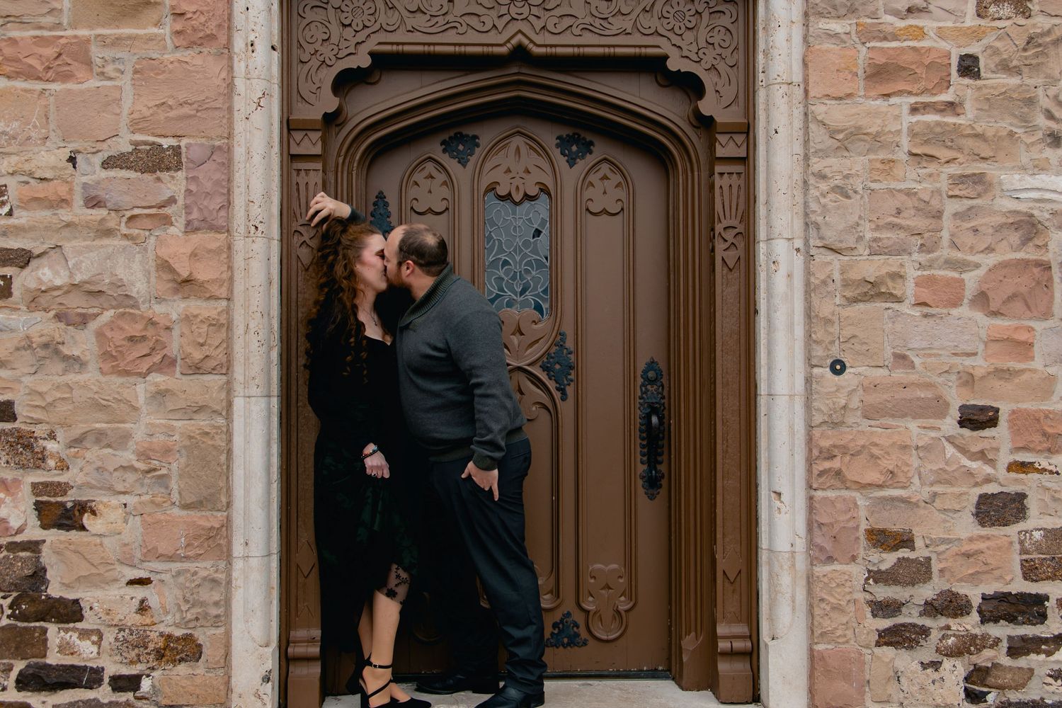 A series of stone archways and wooden doors along a rustic brick wall exterior.