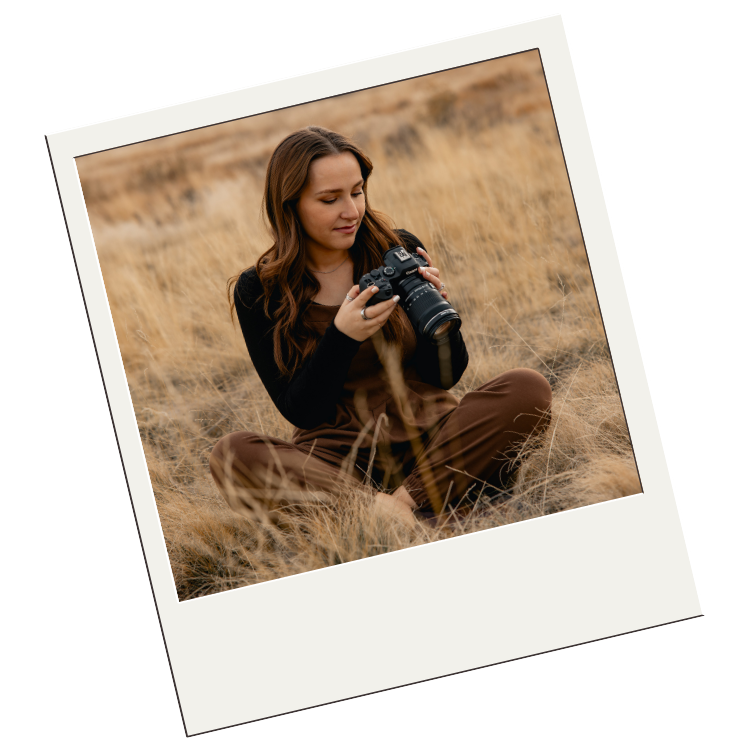 Photographer with long hair in brown sweater captures photos in golden dry grass field during sunset.