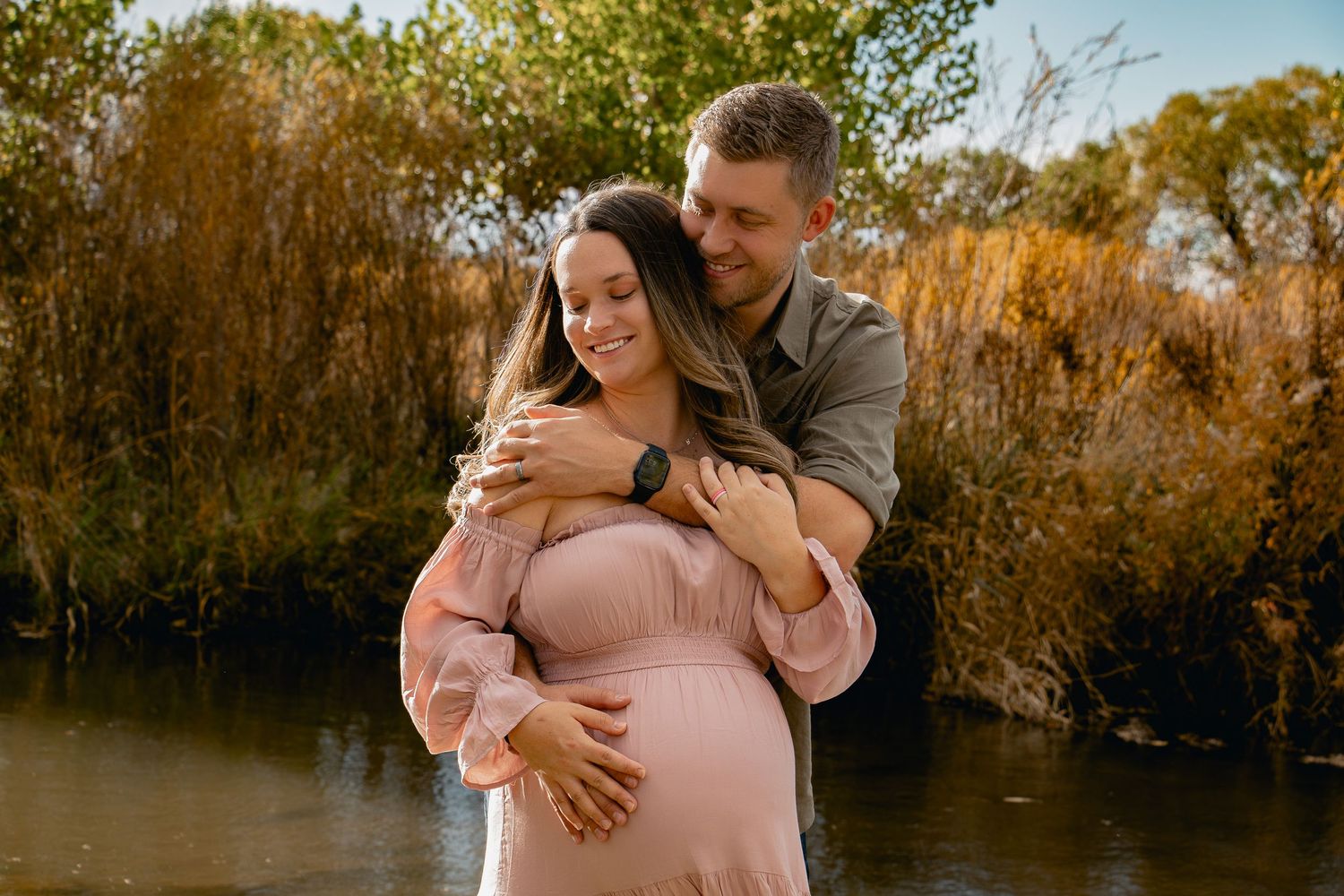 A couple embraces in a romantic outdoor photoshoot with golden autumn foliage in the background.