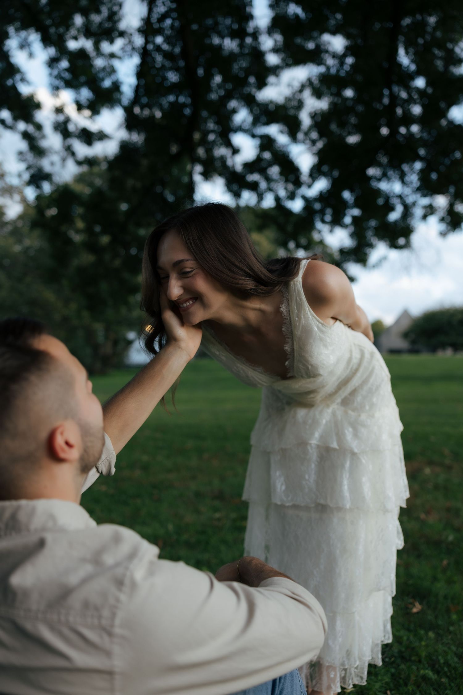A man tenderly touches a smiling woman's face as she leans toward him in a park.