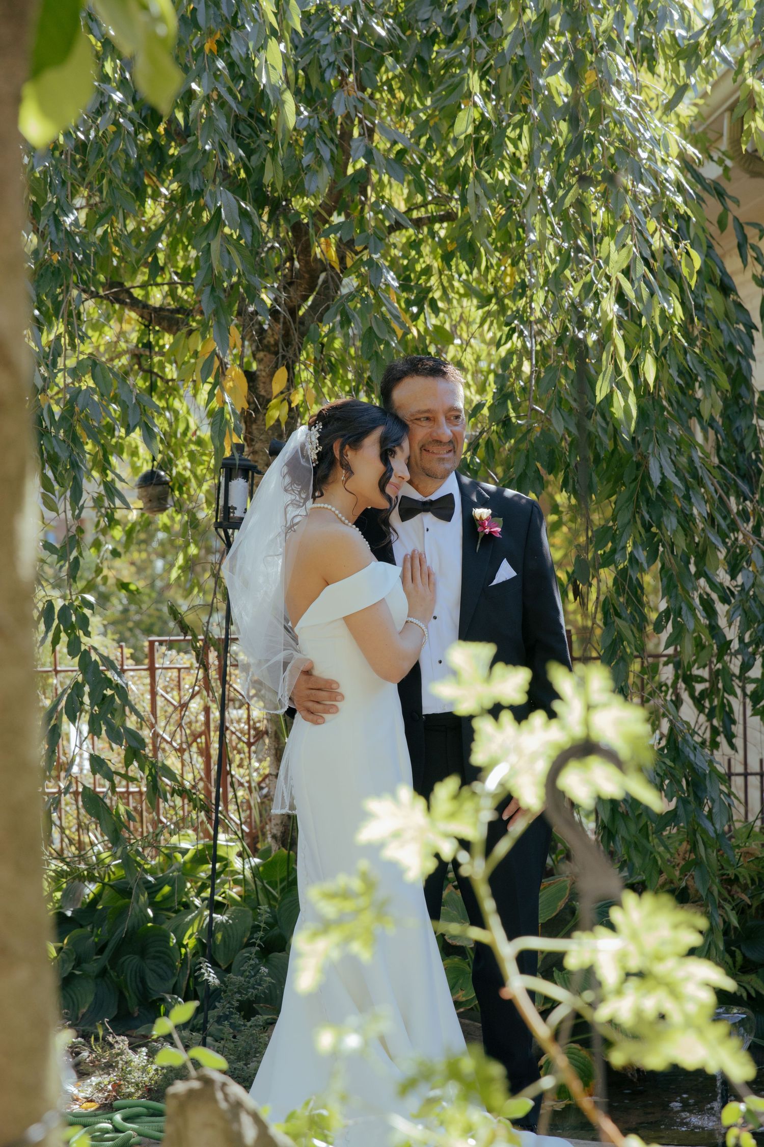 A couple shares a romantic moment under a canopy of eucalyptus trees in their wedding attire.