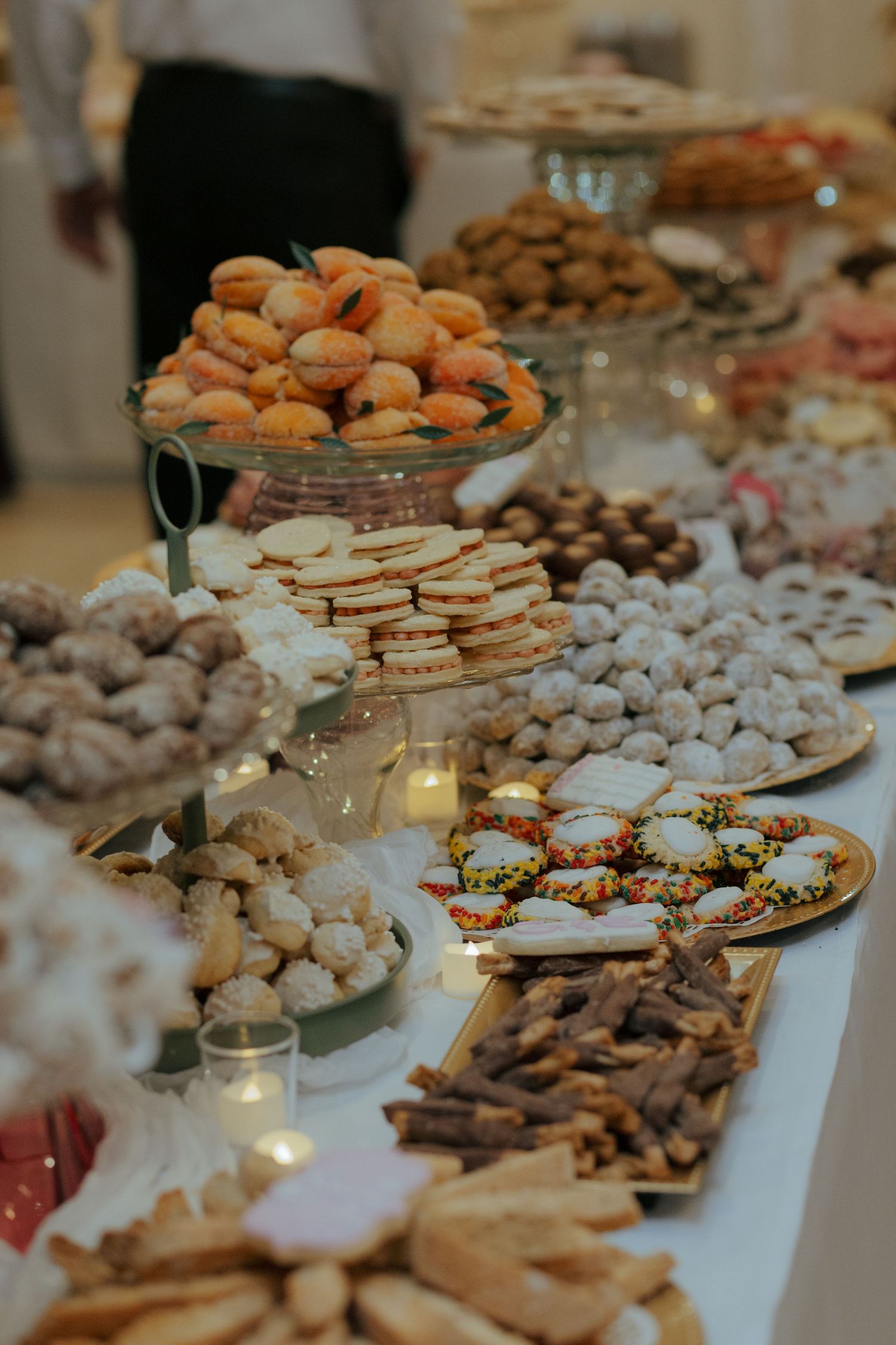 Elegant wedding dessert table with assorted cookies, macarons, and sweets on tiered displays.