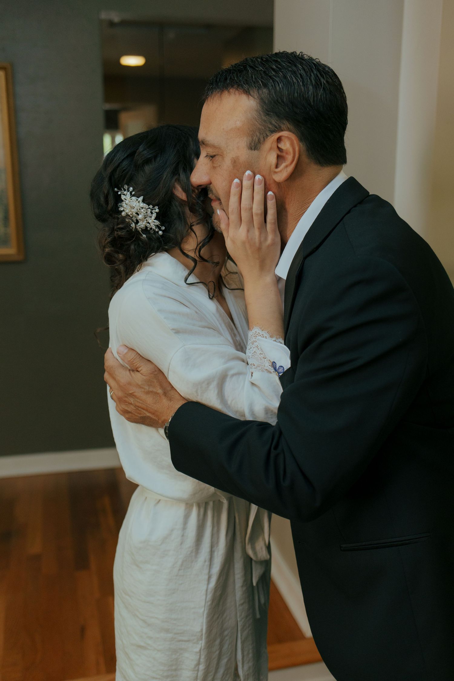 Bride and groom share a romantic kiss during their wedding day first look moment indoors.