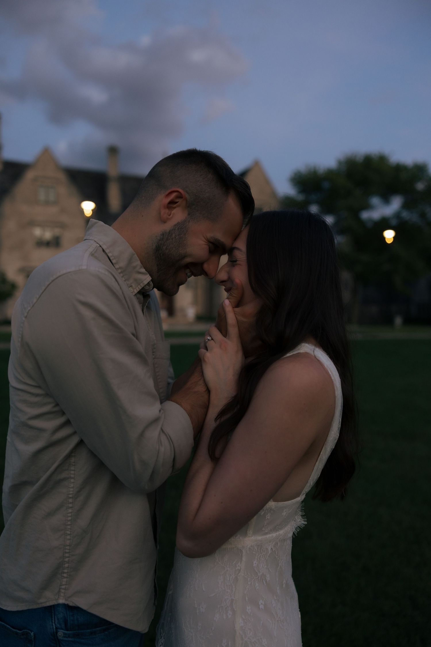 Romantic couple sharing an intimate moment outdoors at twilight, touching foreheads and smiling together.
