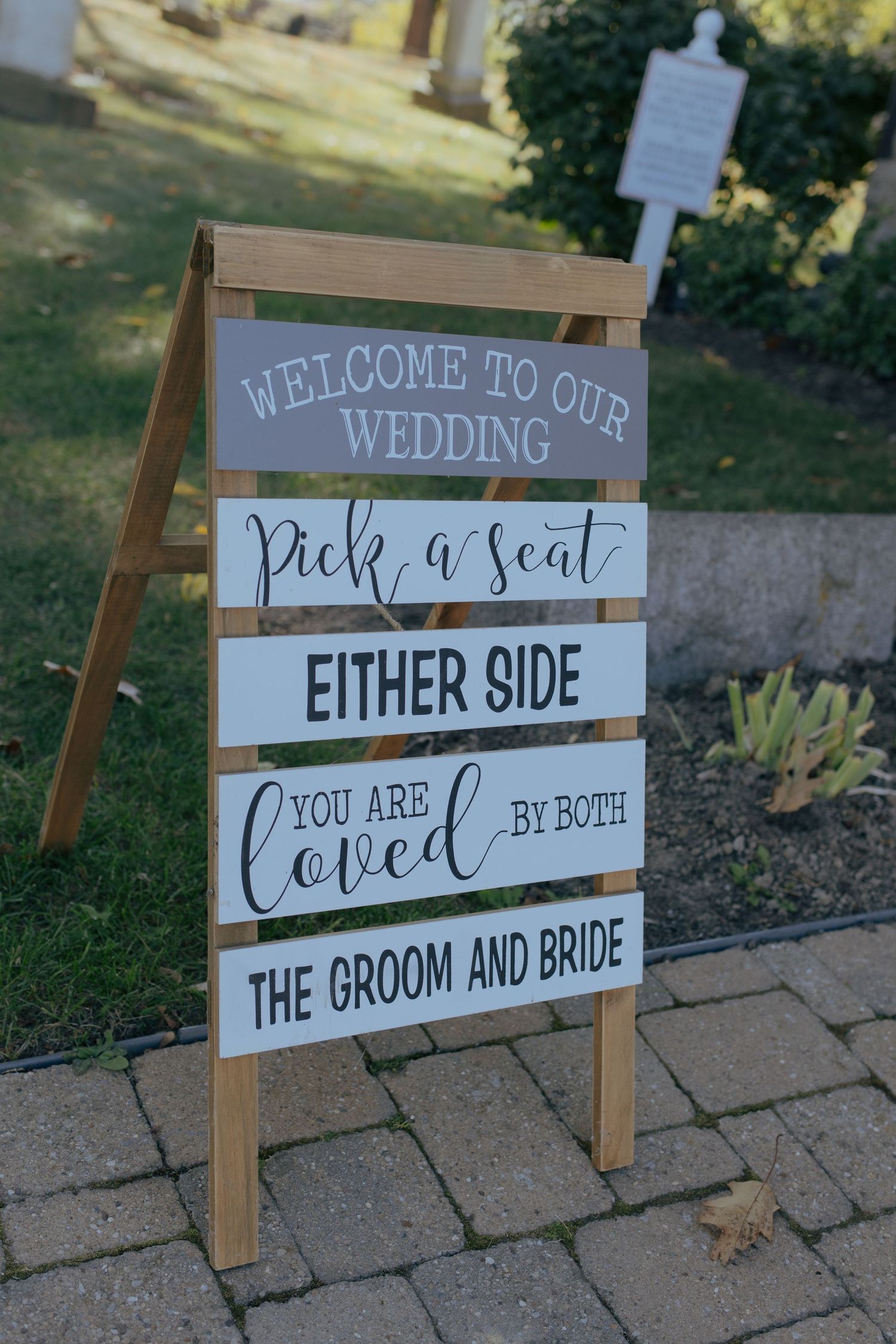 Wedding sign on easel reading Welcome to Our Wedding, Pick a Seat Either Side, You Are Loved by Both the Groom and Bride.
