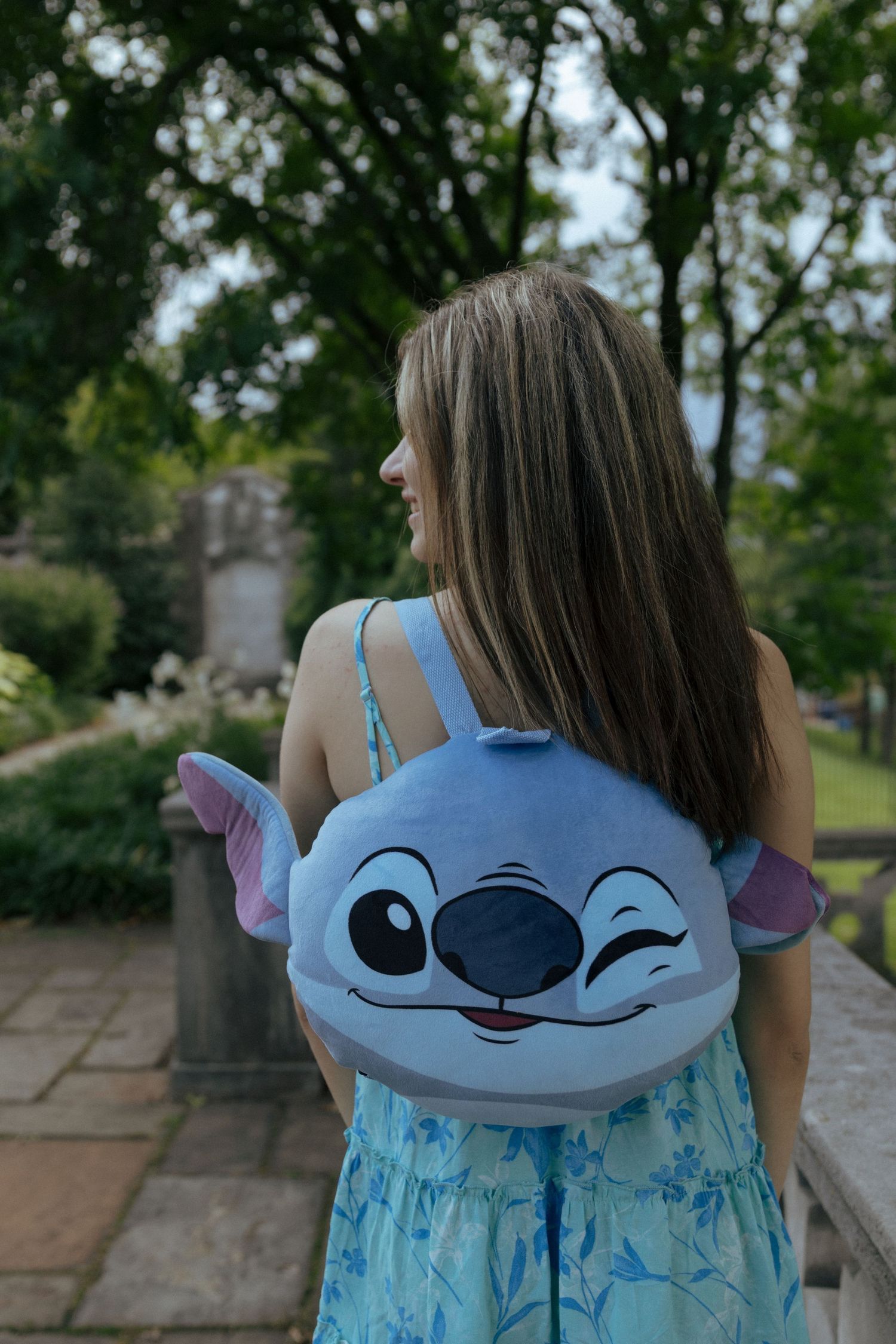 Outdoor portraits featuring a blue Stitch character backpack against stone architecture.