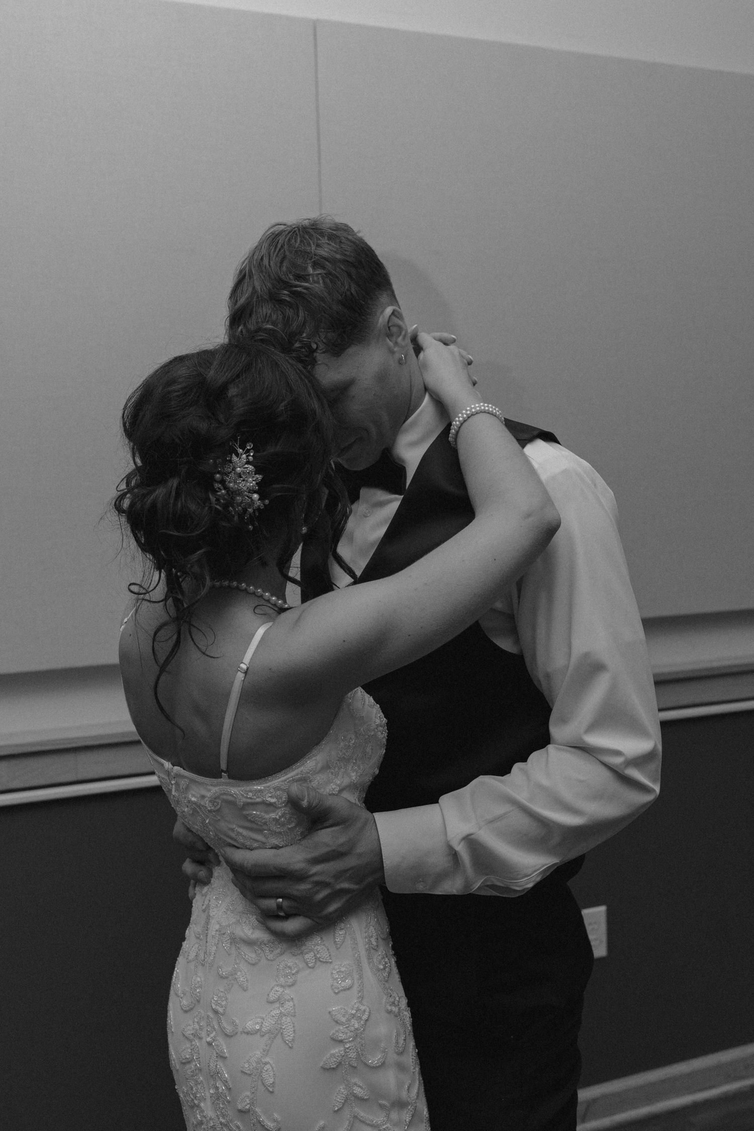 Bride and groom share a romantic kiss during their first dance in a black and white photo.