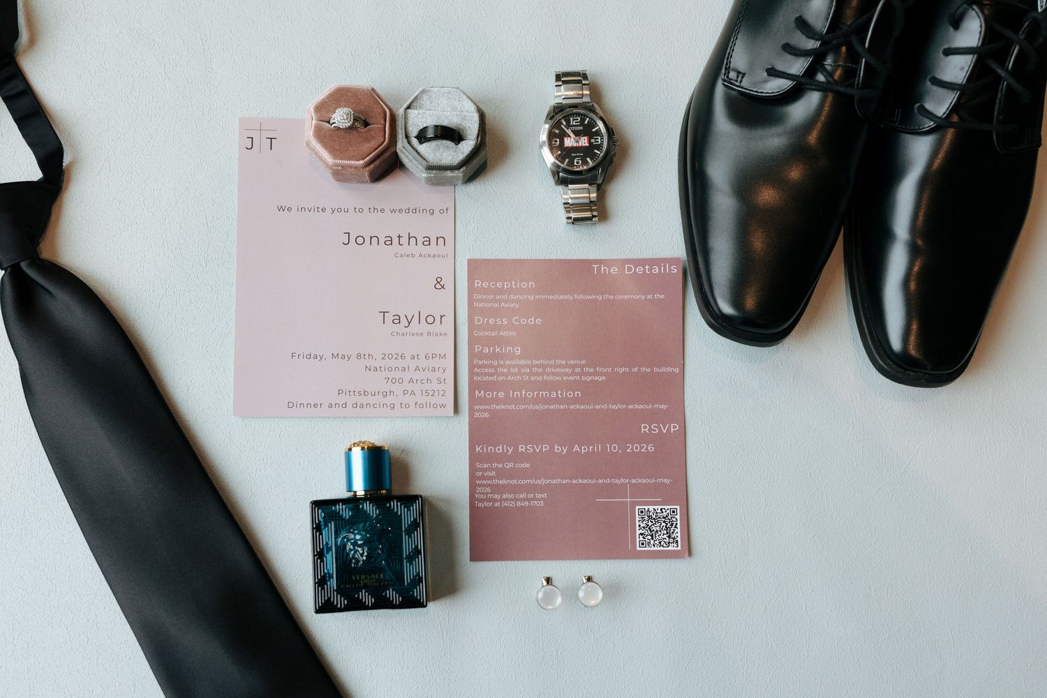 Groom wedding flat lay with invitation suite, cologne, cufflinks, watches, tie, and black dress shoes.