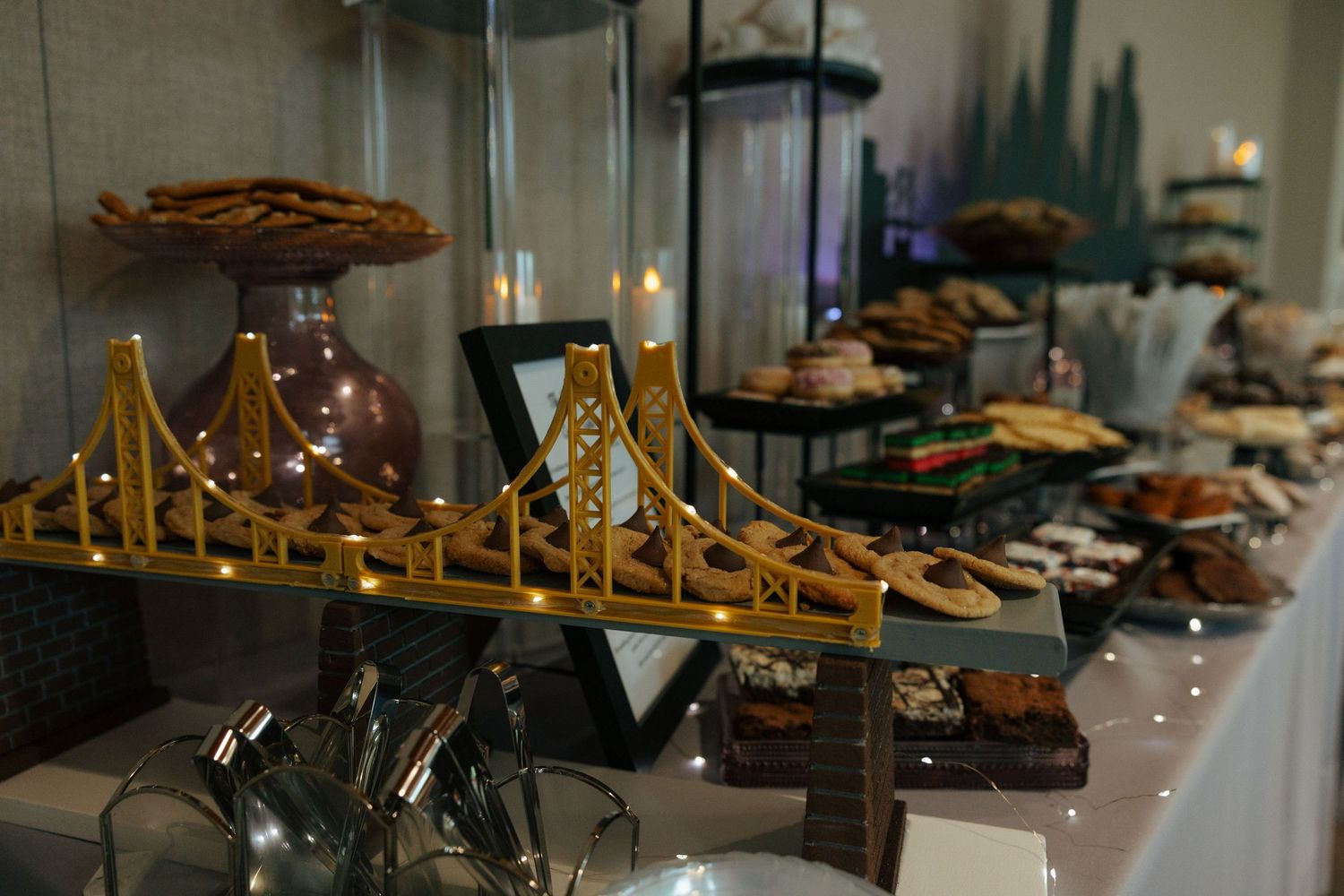 Golden Gate Bridge model centerpiece on a dessert table with assorted pastries and treats at an elegant event.