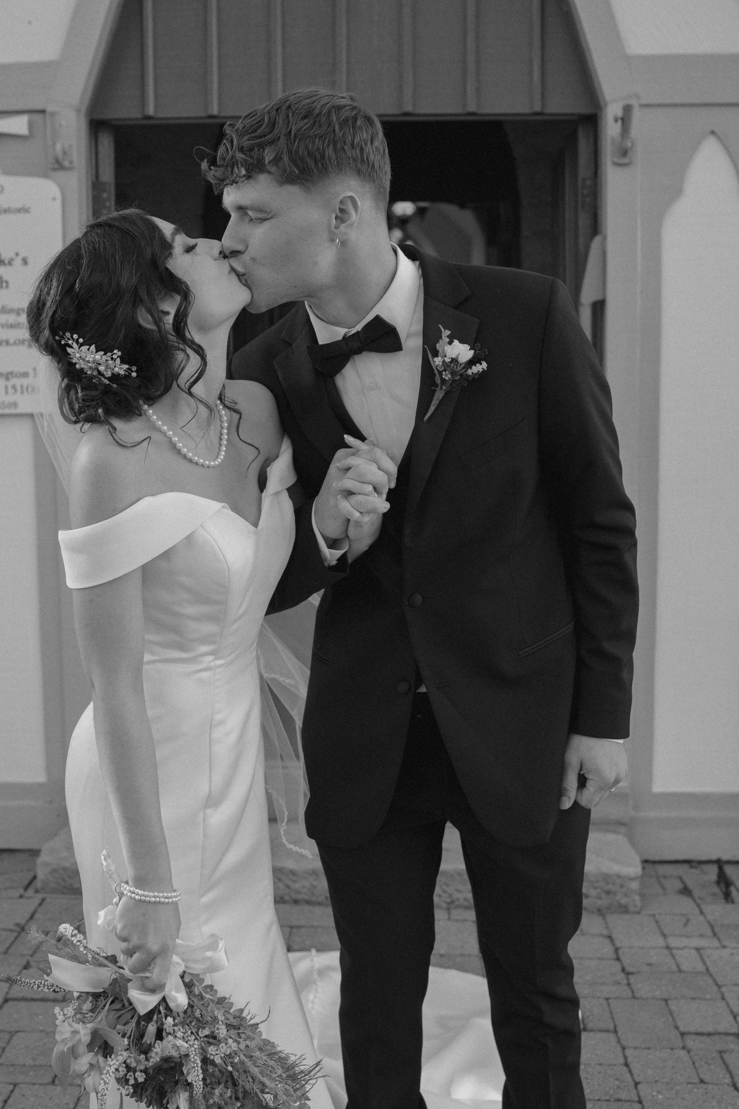 Bride and groom share first kiss outside stone church.