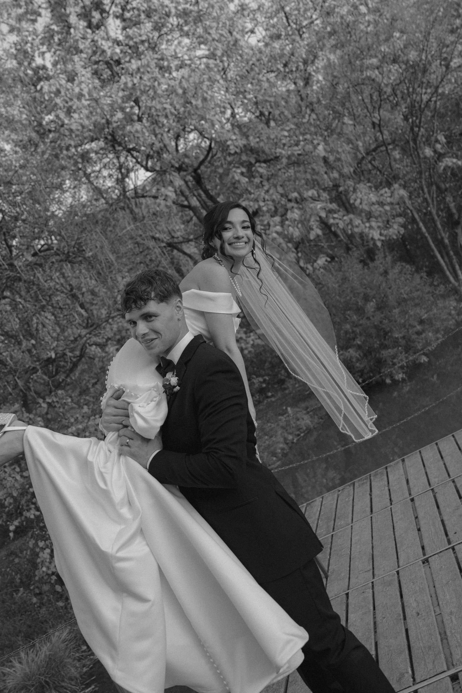 Black and white wedding photos on a wooden deck surrounded by autumn trees.