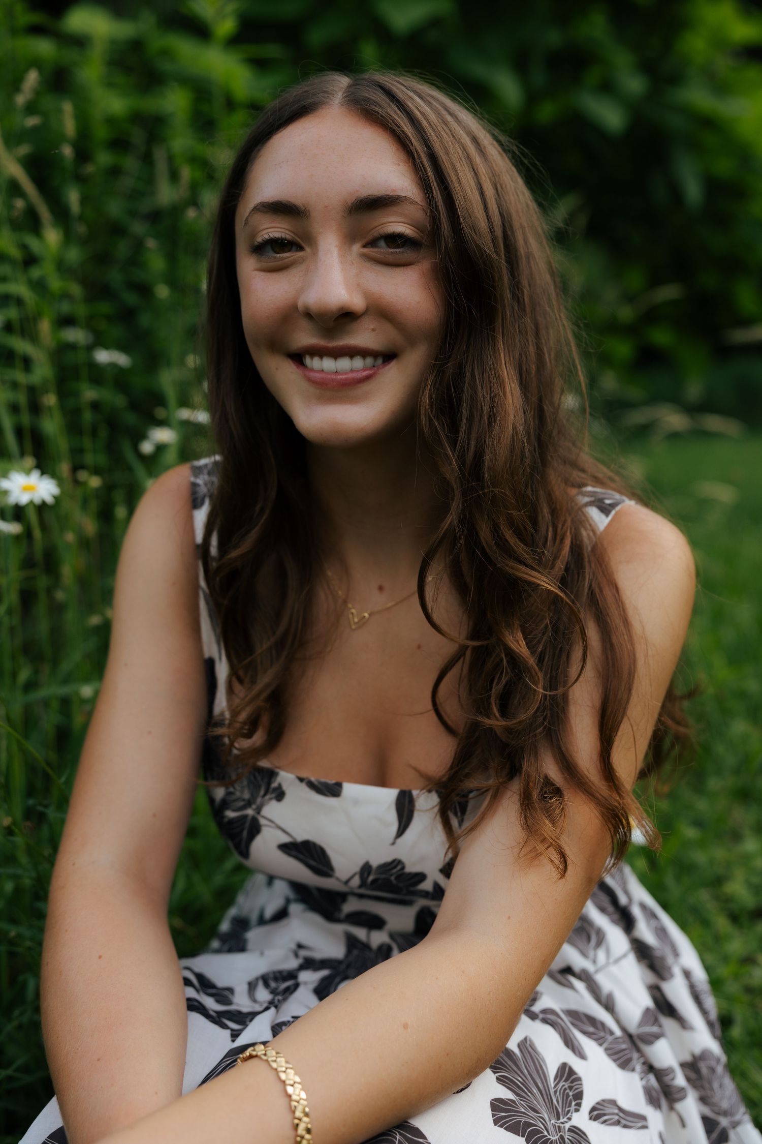 Smiling brunette woman in black and white floral dress outdoors.