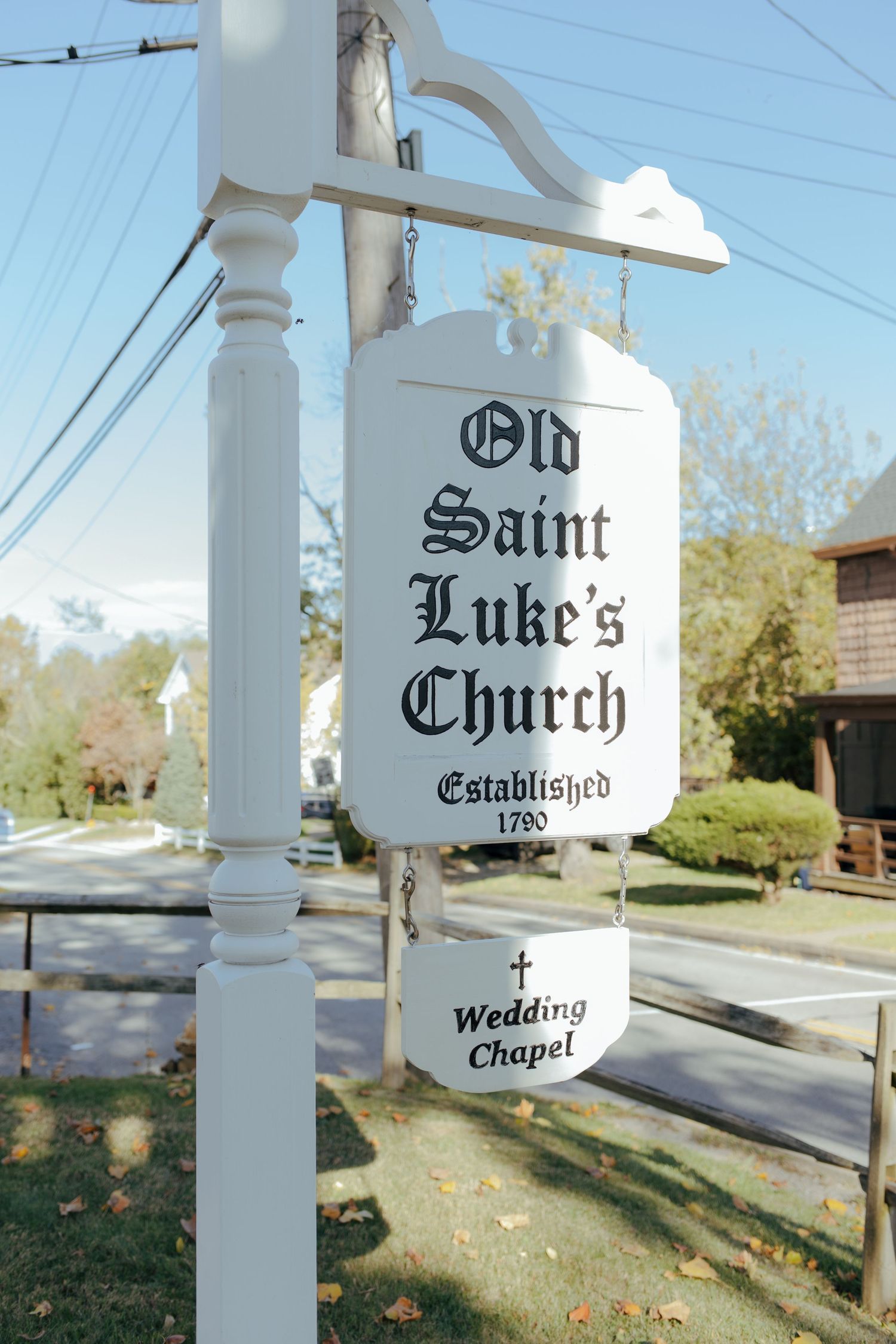 White sign for Old Saint Luke's Church established 1790, featuring a Wedding Chapel placard on a decorative post.