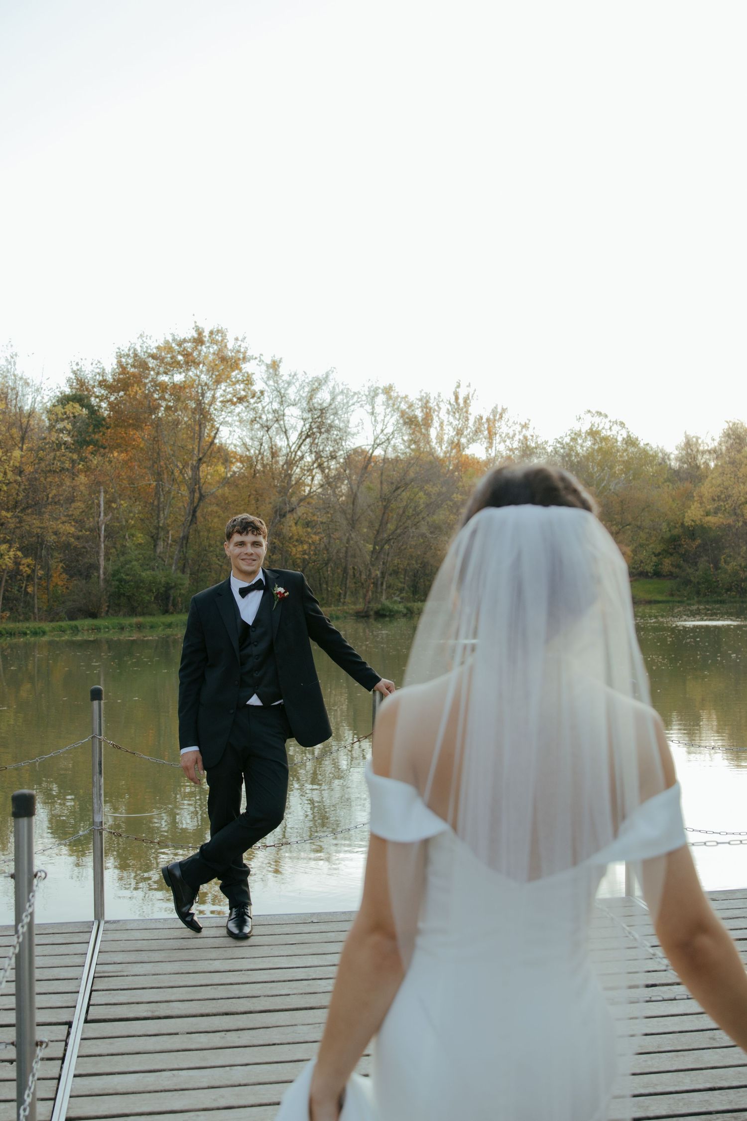 A series of playful wedding photos on a wooden dock by a lake during golden hour.