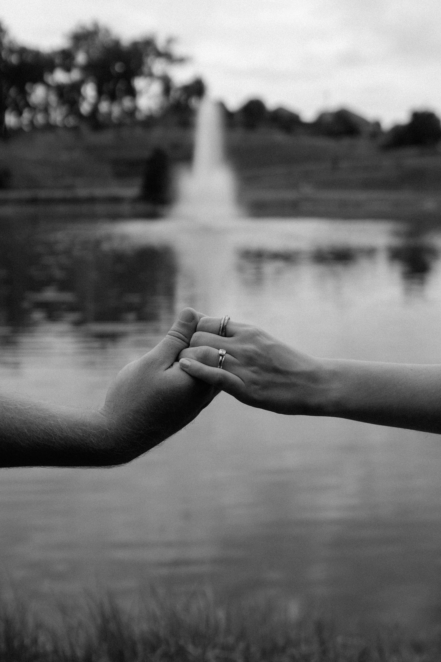 A series of black and white images showing hands reaching towards each other across a blurred lake landscape.