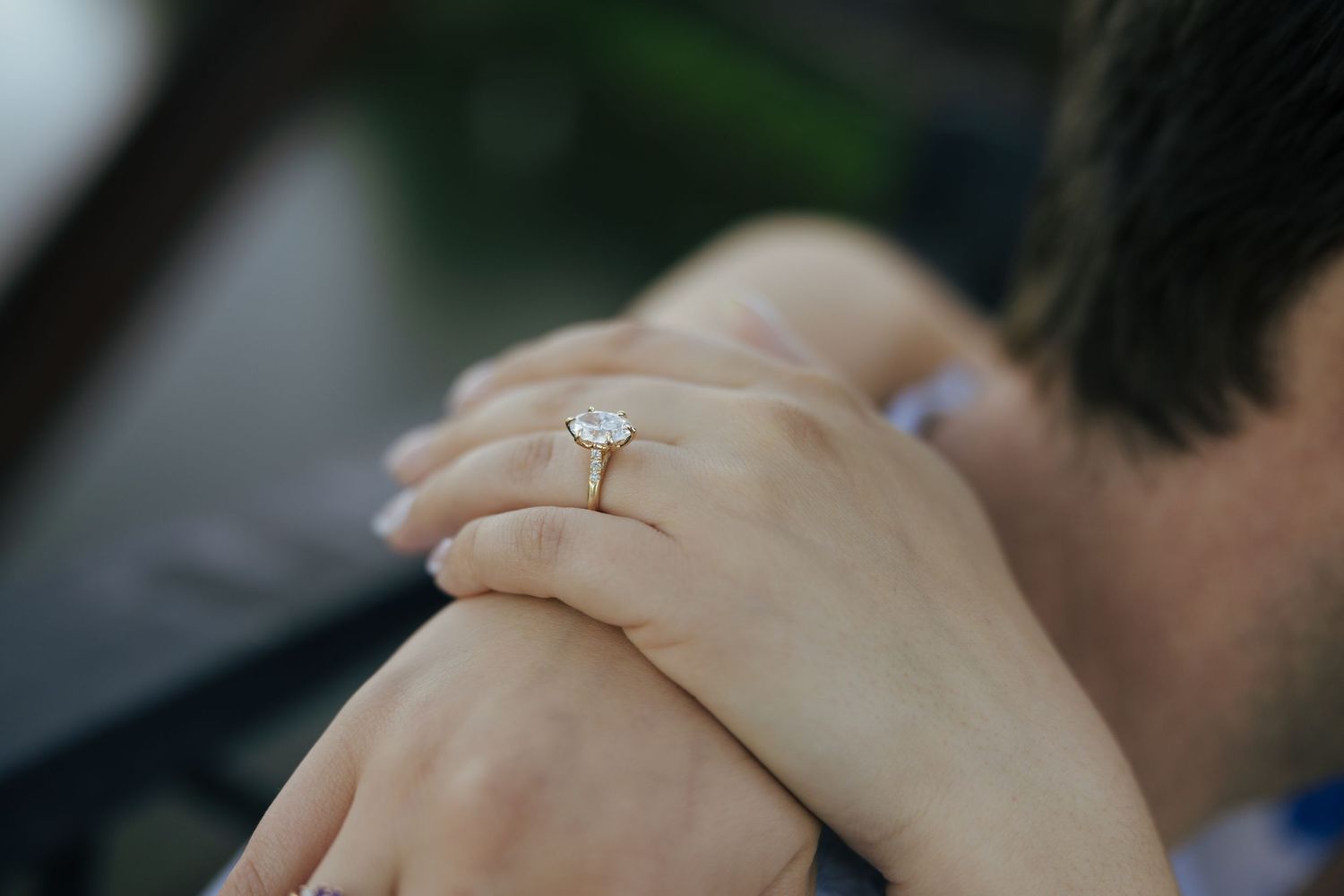 Close-up of an elegant oval diamond engagement ring on a woman's hand.