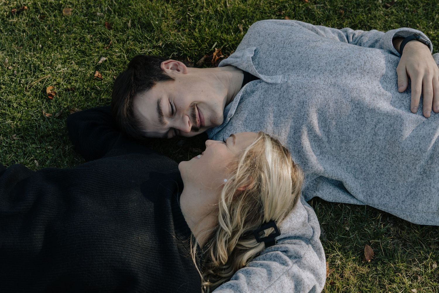 Person in gray sweater lying on grass in multiple artistic poses showing movement and contemplation.