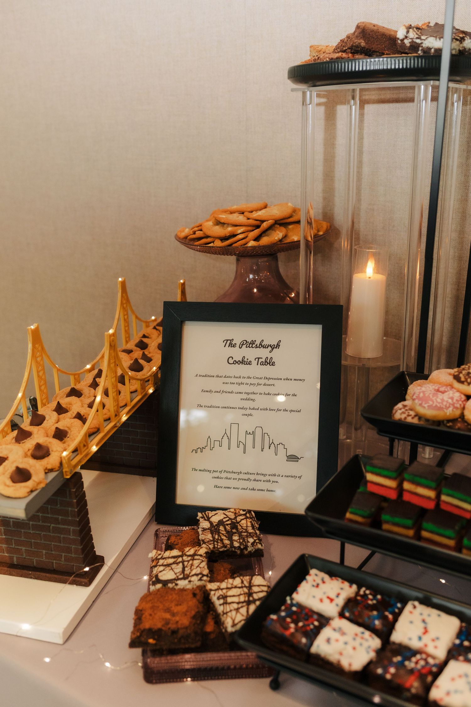 Pittsburgh cookie table display with assorted cookies, brownies, and sweets alongside a framed sign and lit candle.