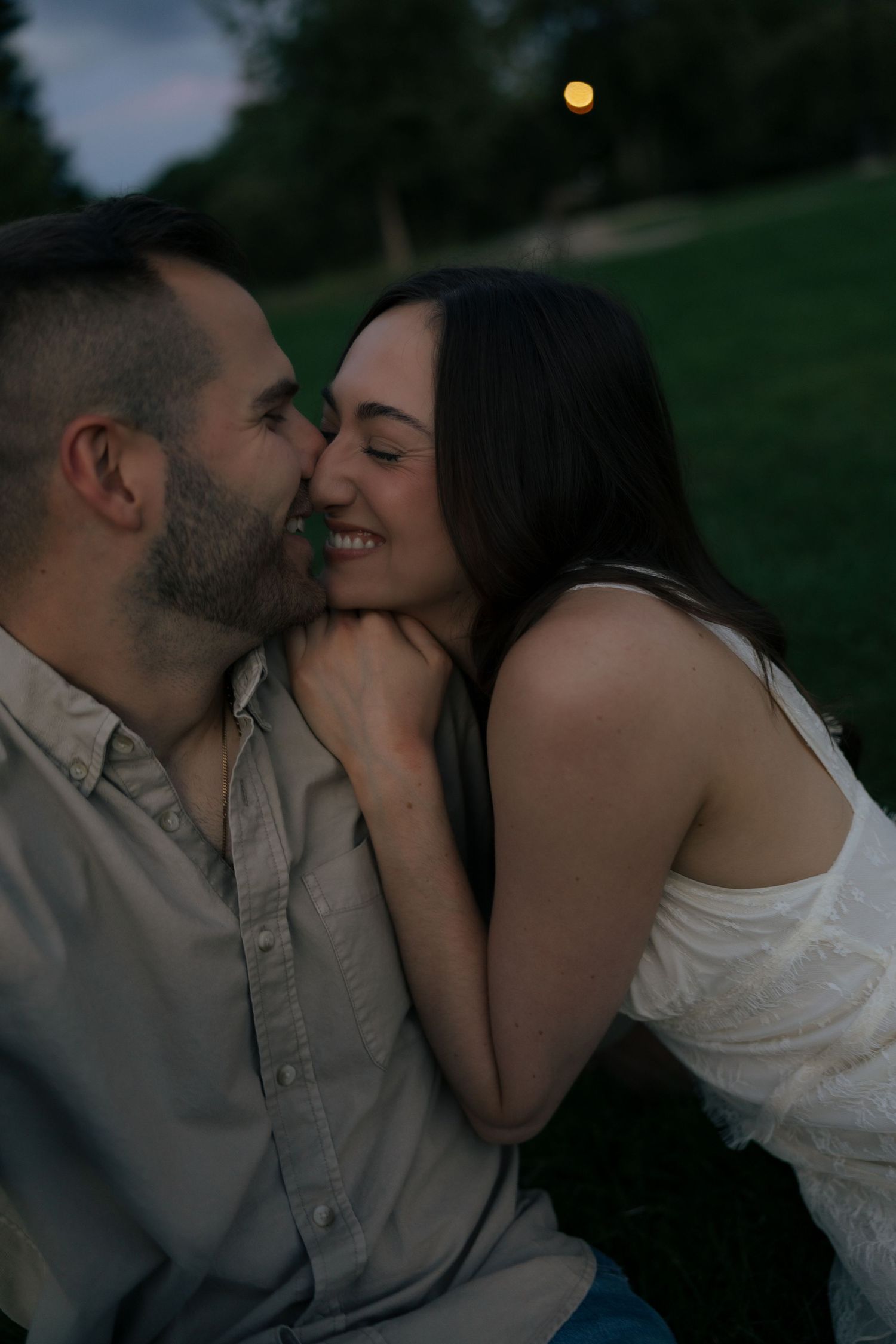 Couple shares intimate moment as groom kisses brides cheek in soft evening light.