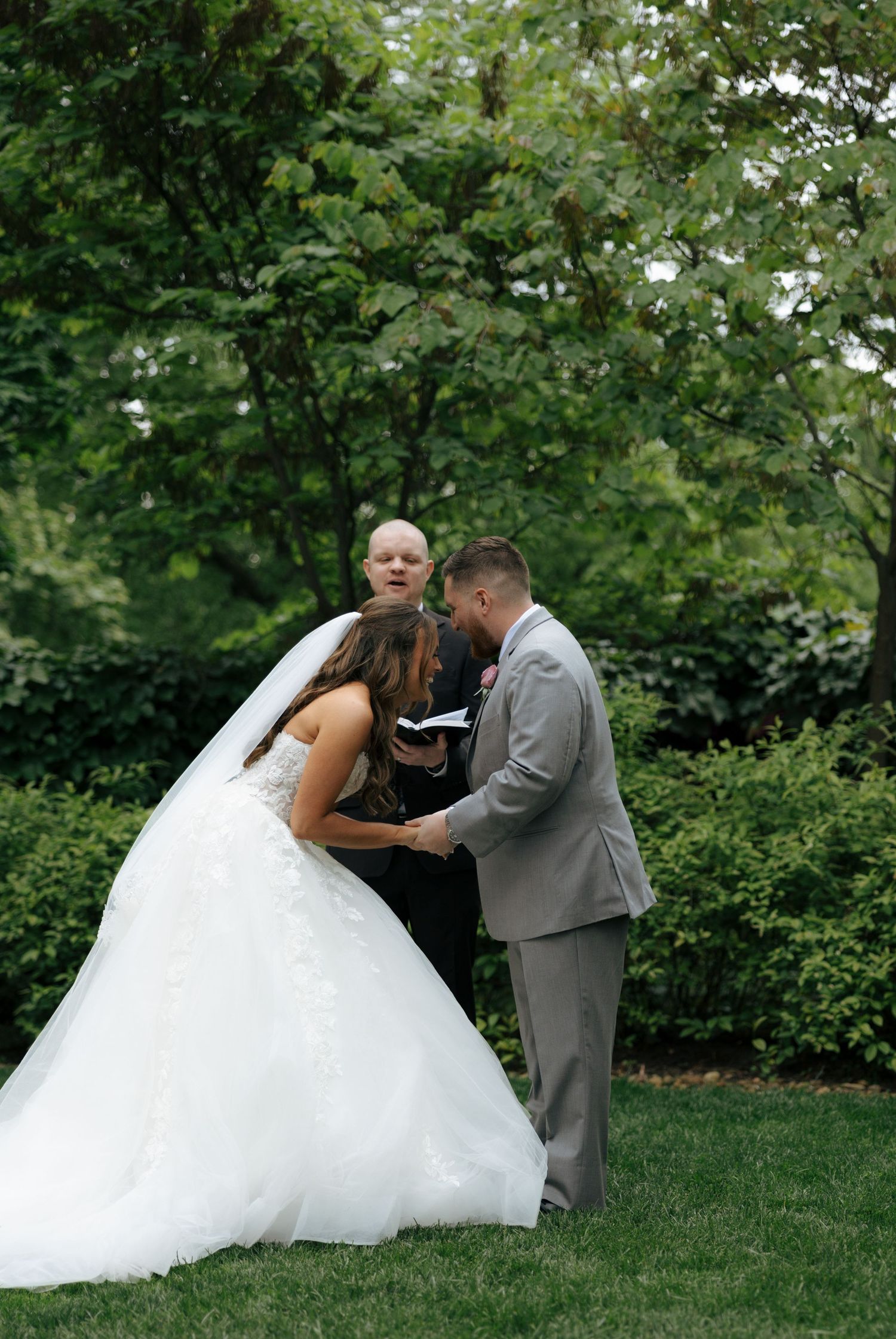 Bride and groom exchanging vows with officiant in lush garden wedding ceremony.