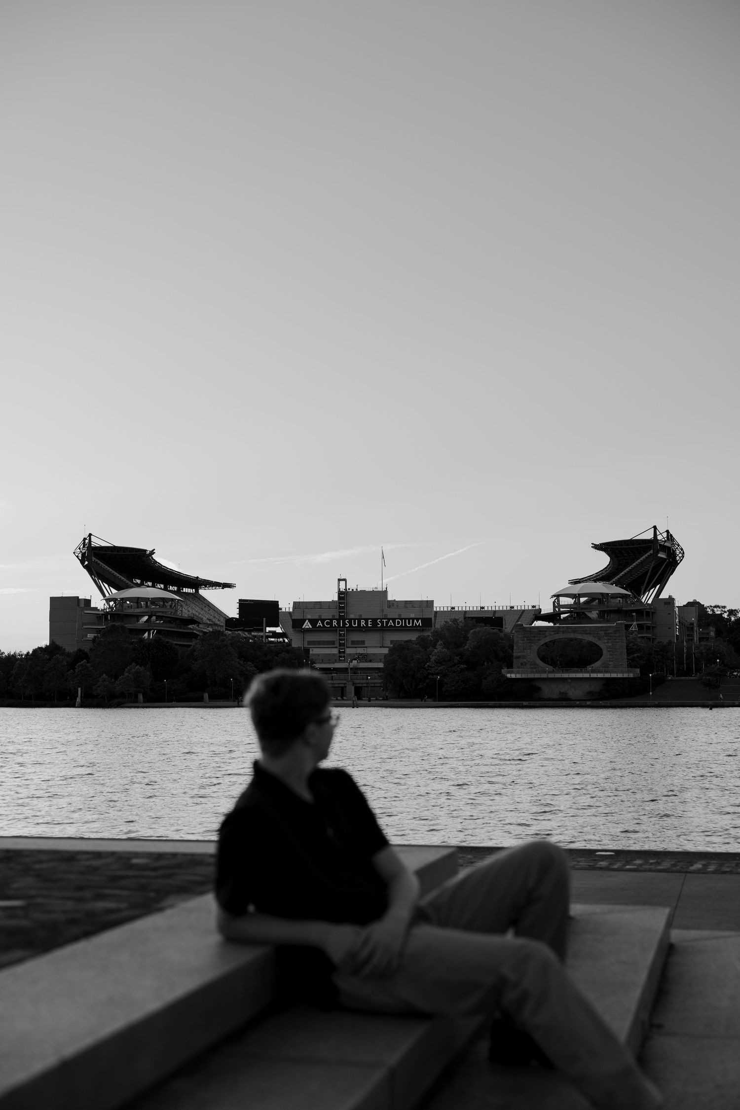 Silhouette of teen sitting on steps facing Acrisure Stadium.