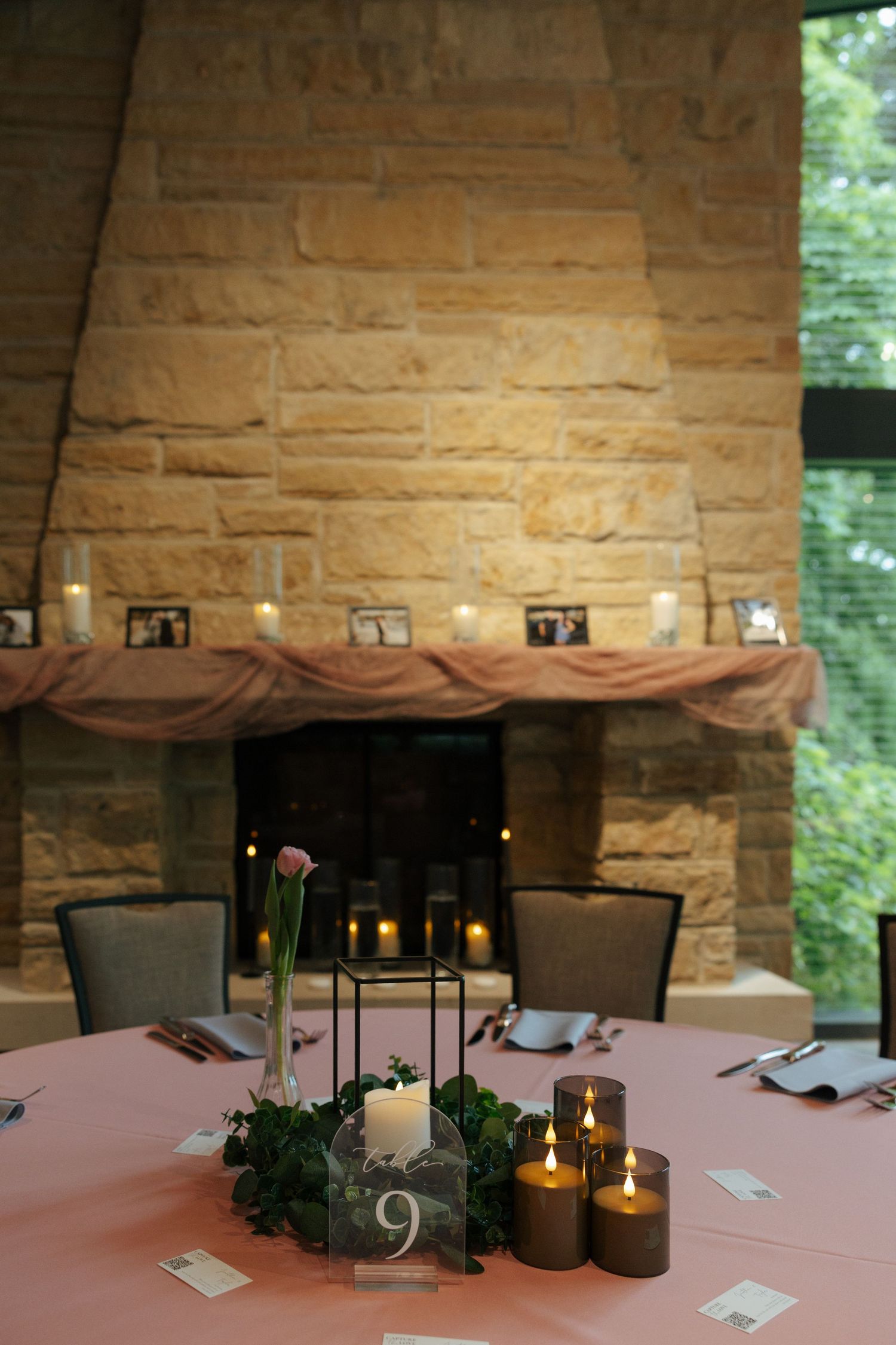 Elegant wedding reception table with candles and floral centerpiece in front of a stone fireplace.
